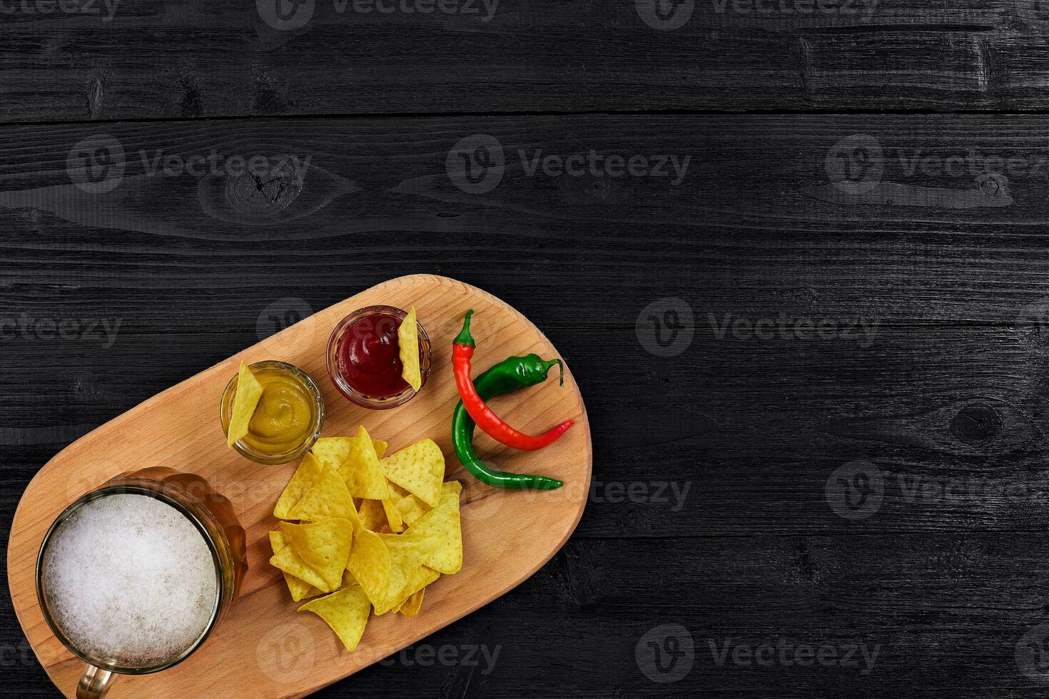 Glass of beer with nachos chips on a wooden background. photo