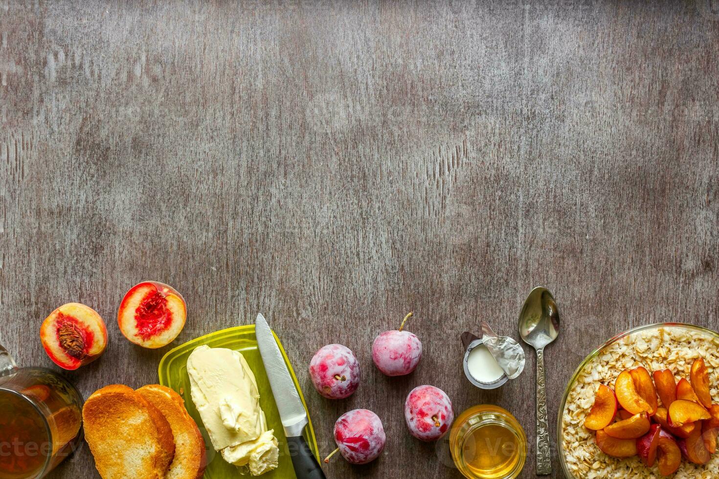 Oatmeal with plums and peach, toast with butter and honey on a wooden table. The concept of a healthy breakfast photo