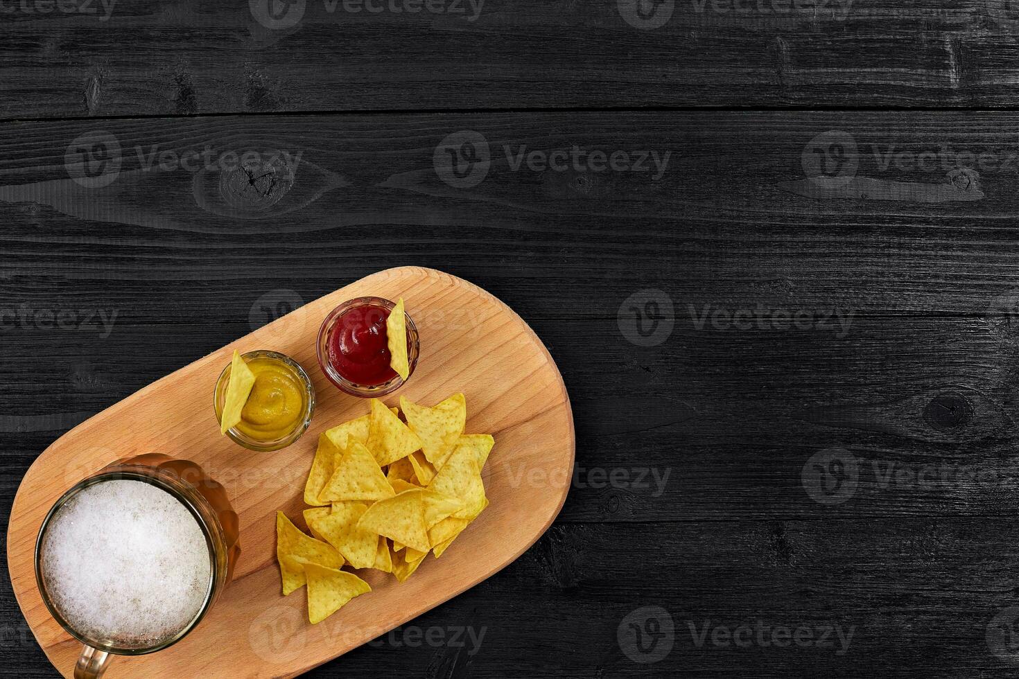 Glass of beer with nachos chips on a wooden background. photo