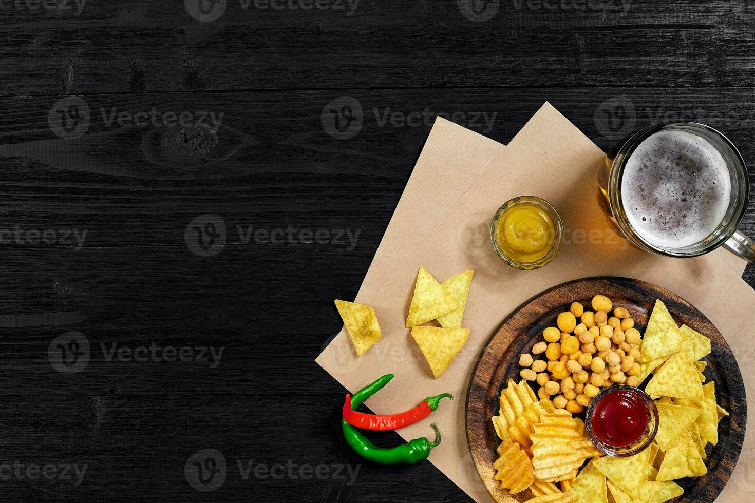 Lager beer and snacks on black wooden table. Nuts, chips. Top view with copyspace photo