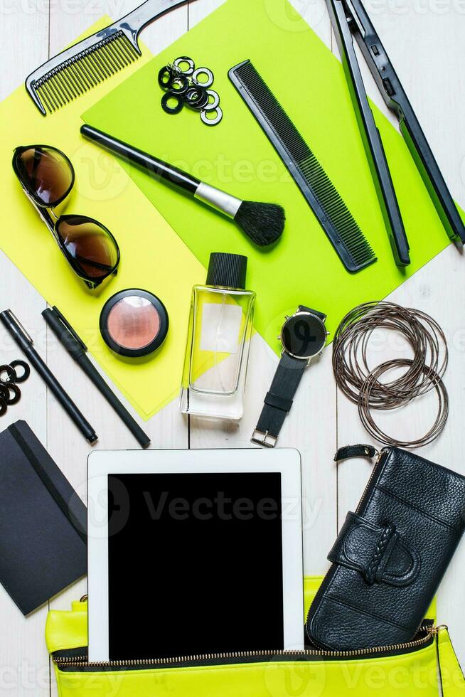 Cosmetics and women's accessories fell out of the green handbag on white background. photo