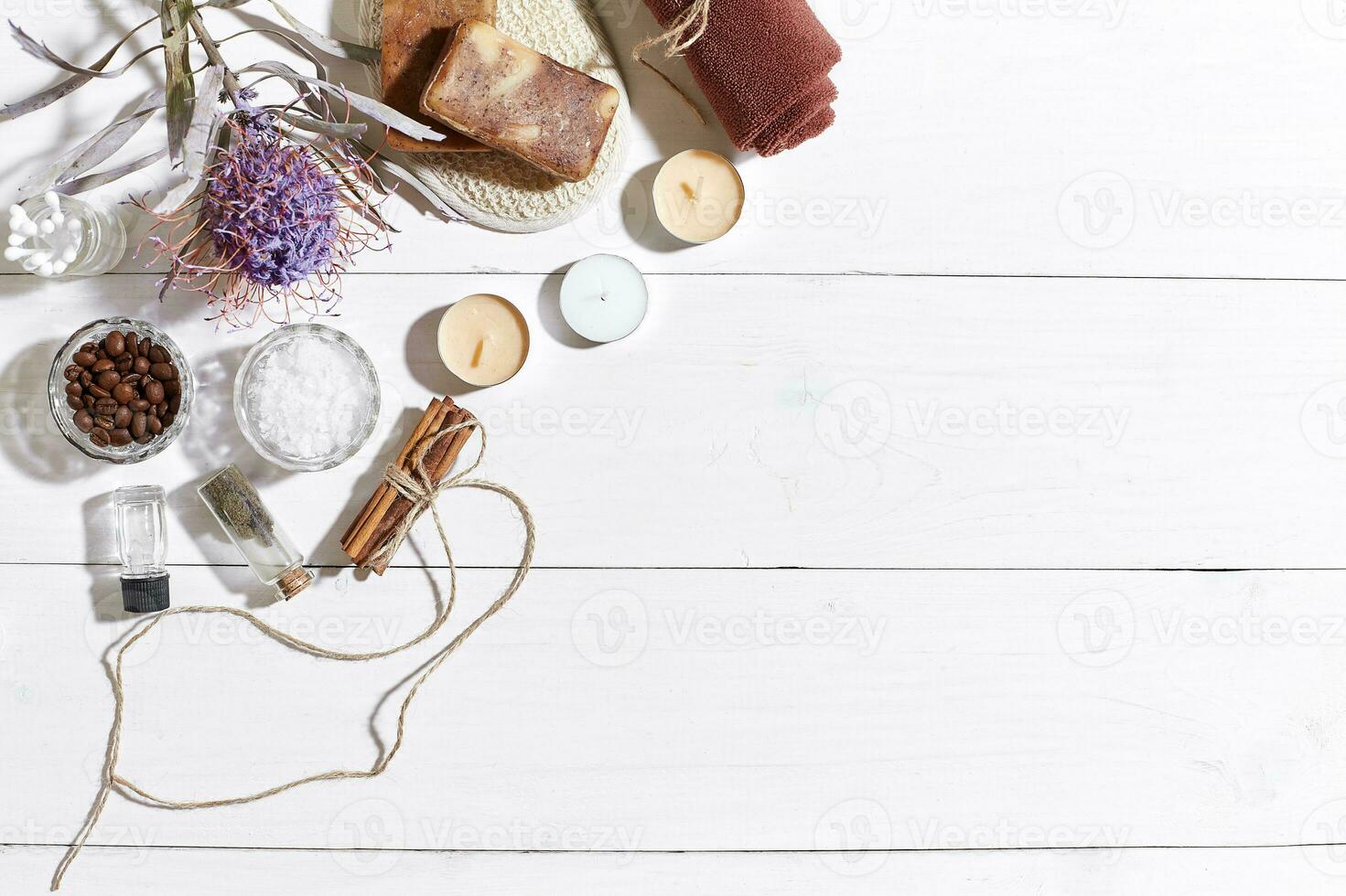 Spa set with sea salt, essential oil, soap and towel decorated with dry flower on white wooden background photo
