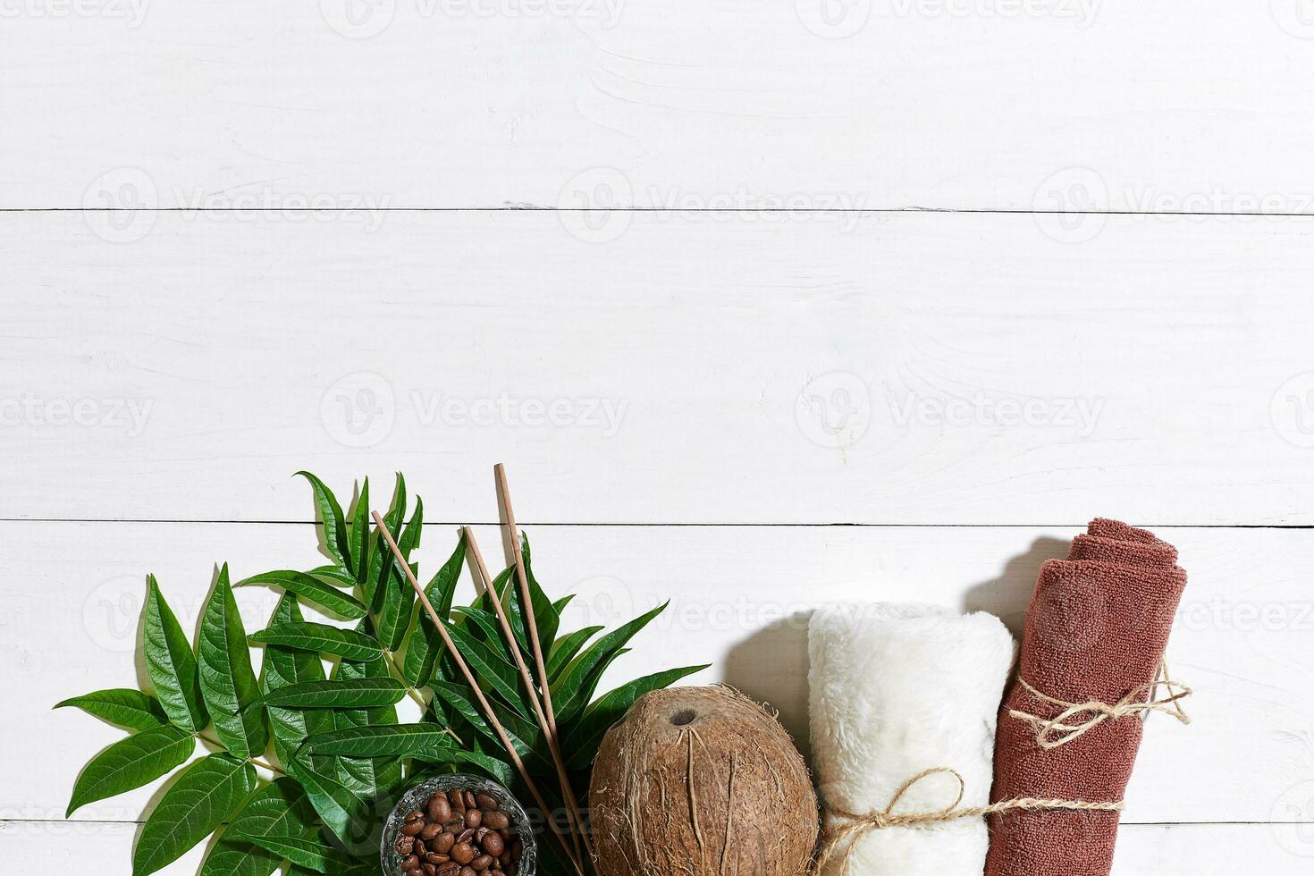 SPA still life with towel, candles and green leaves on a white wooden surface photo