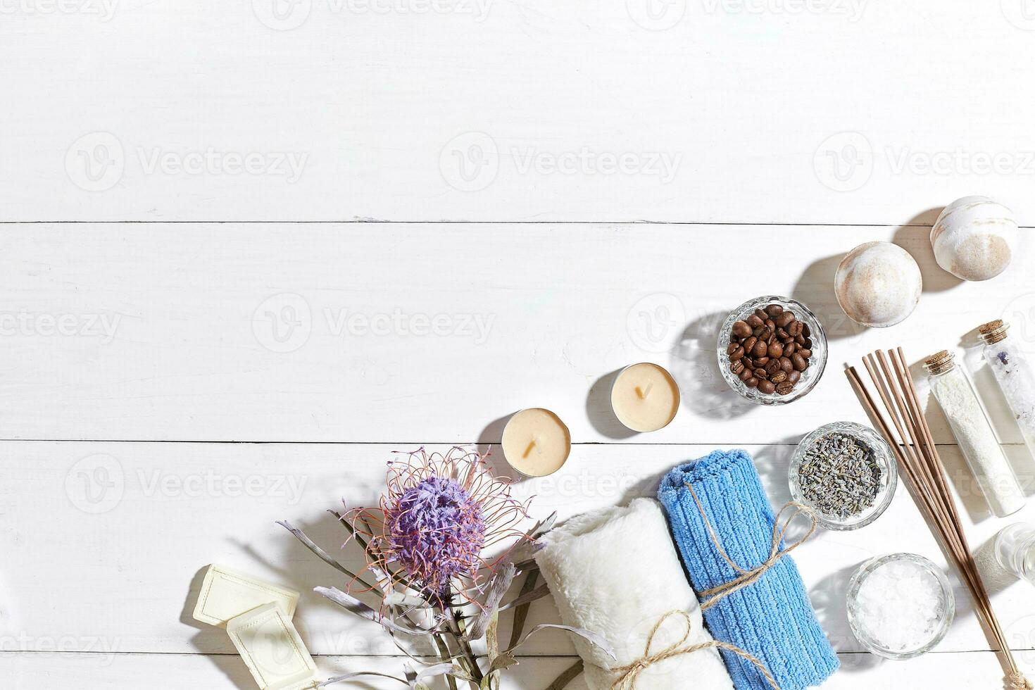 Spa set with sea salt, essential oil, soap and towel decorated with dry flower on white wooden background photo