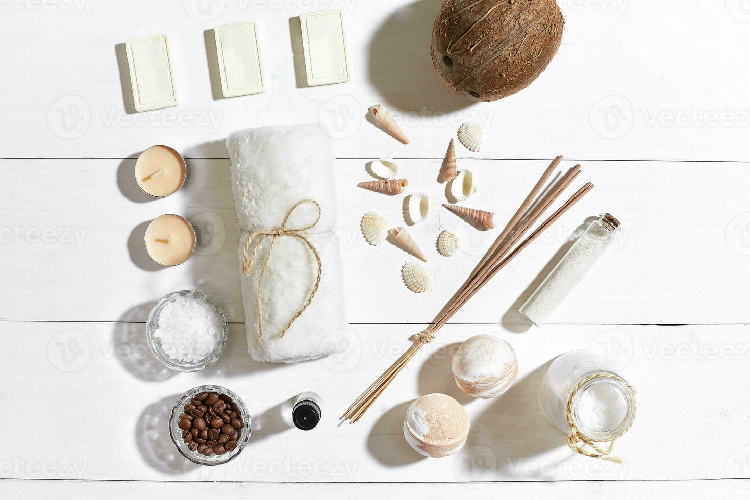 Spa set with sea salt, essential oil, soap and towel decorated with seashells on white wooden background photo