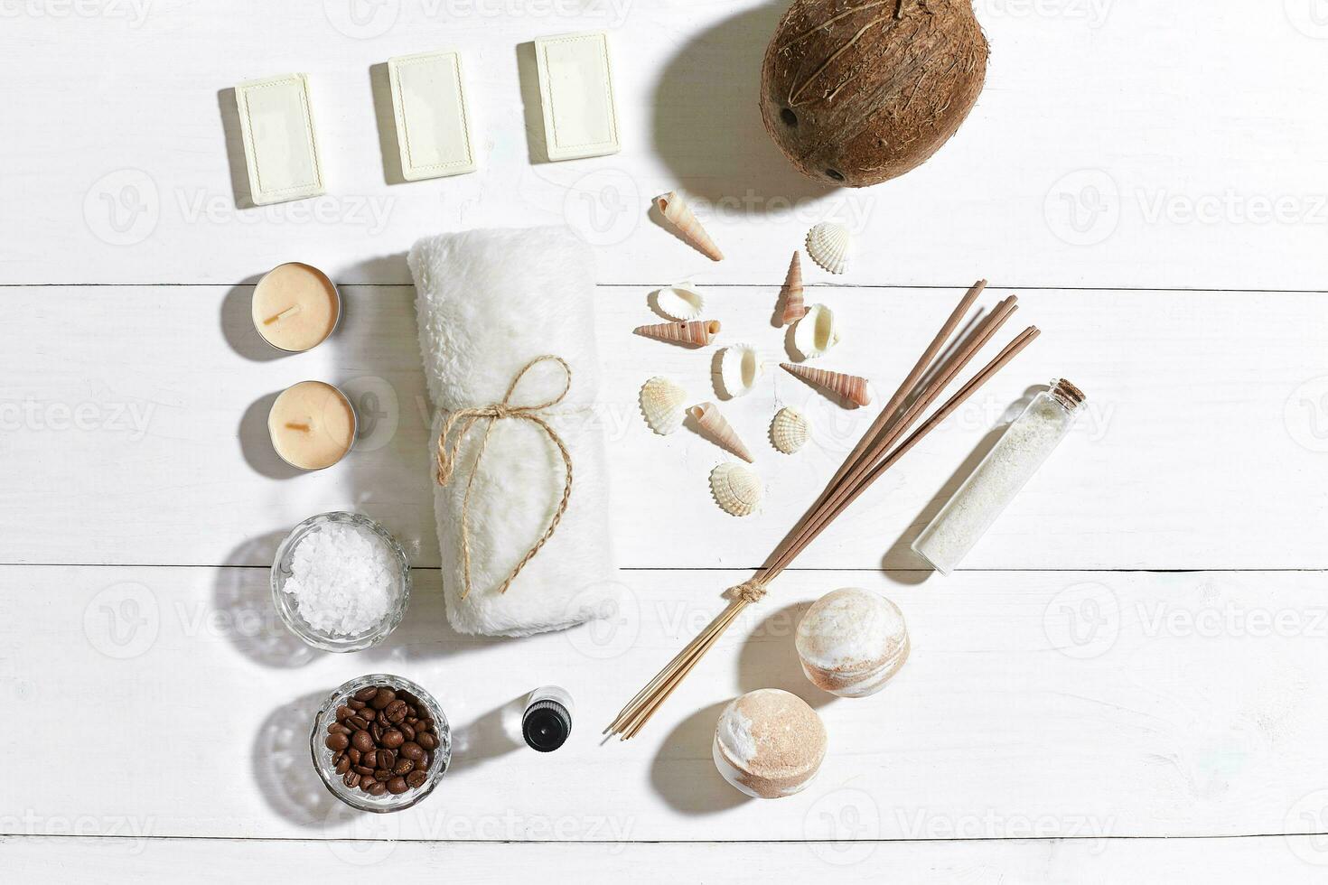 Spa set with sea salt, essential oil, soap and towel decorated with seashells on white wooden background photo
