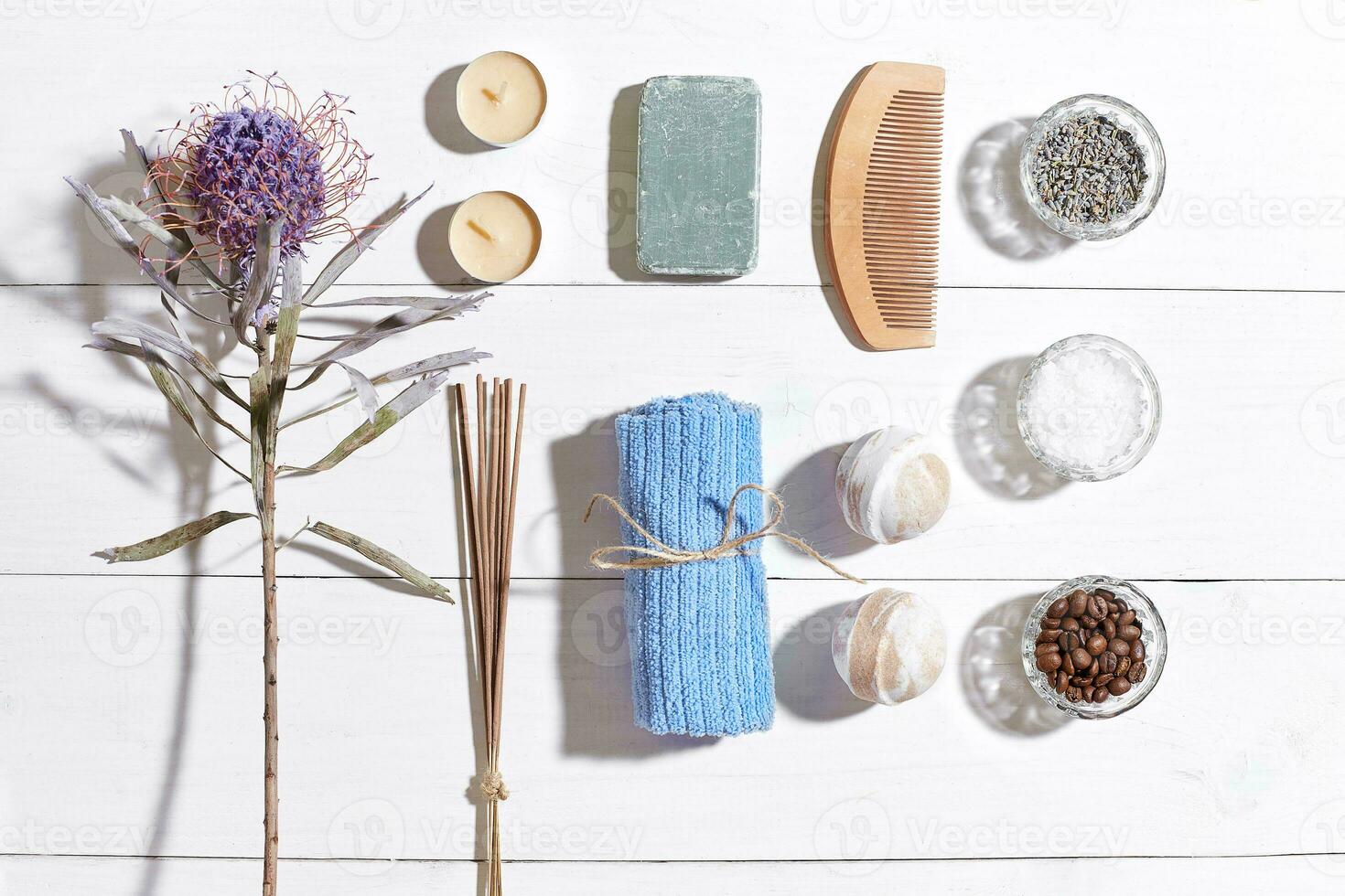 Spa set with sea salt, essential oil, soap and towel decorated with dry flower on white wooden background photo