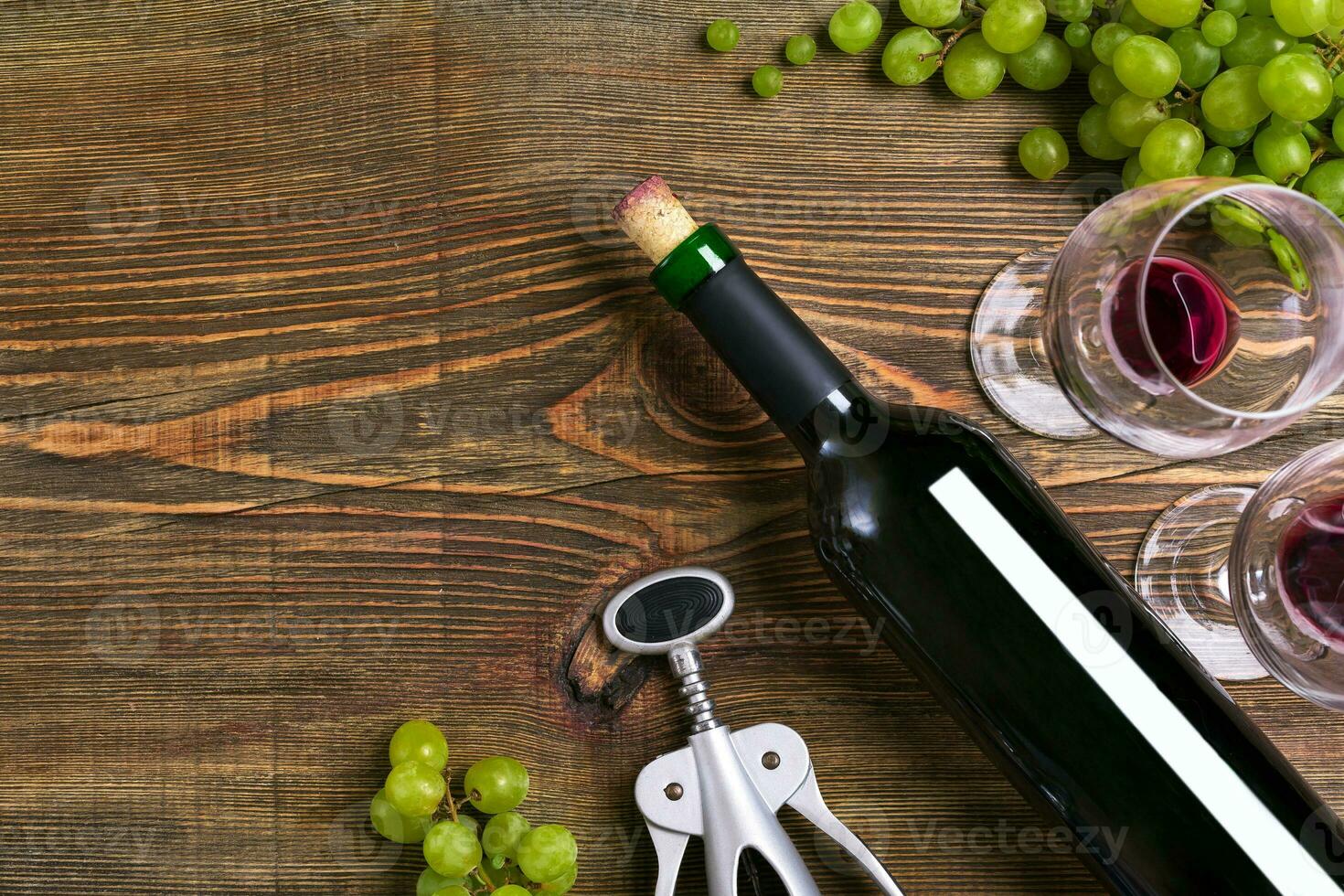 Red wine bottle, grape, chocolate and glasses over wooden table. Top view with copy space photo