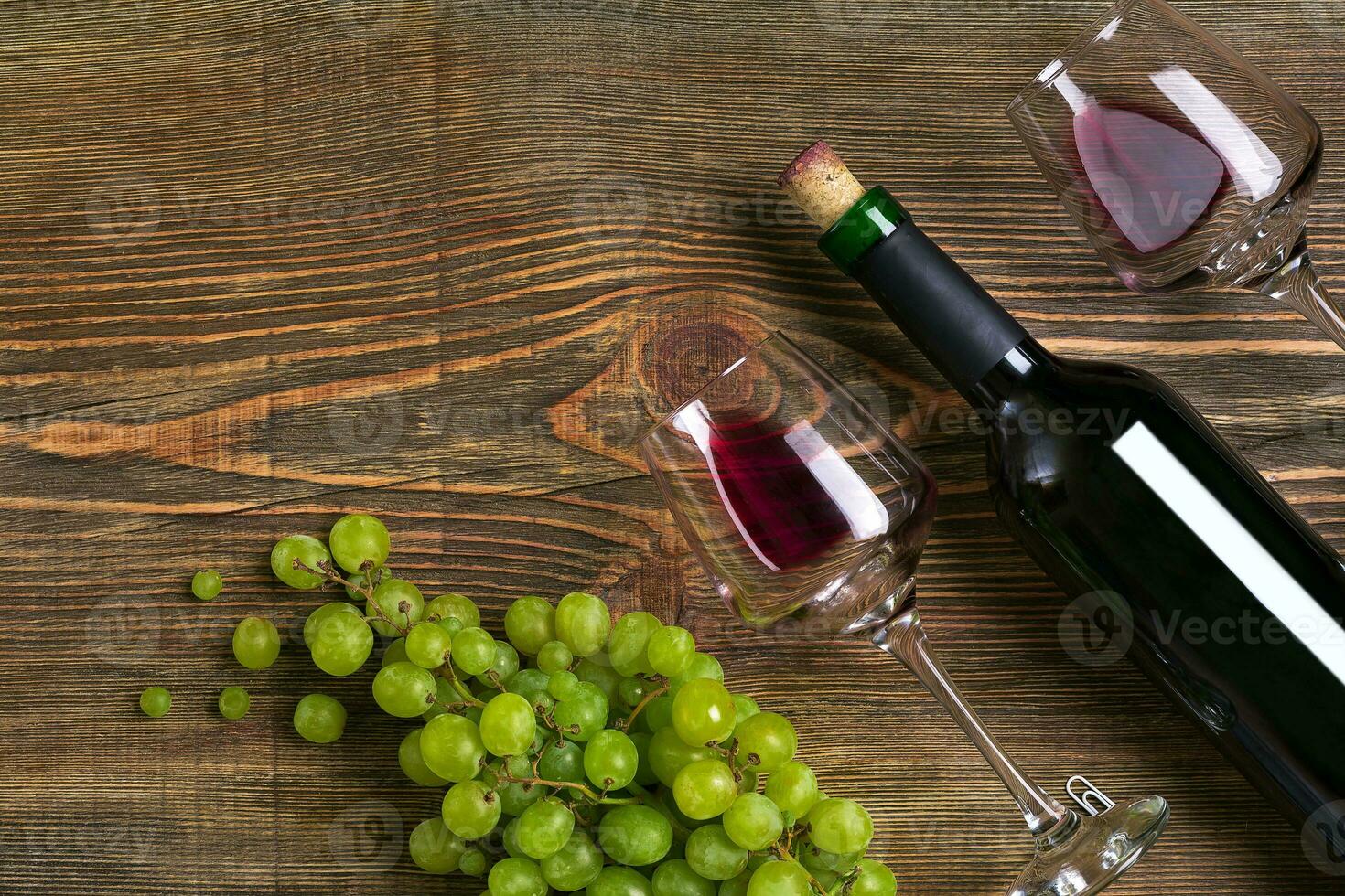 Red wine bottle, grape, chocolate and glasses over wooden table. Top view with copy space photo