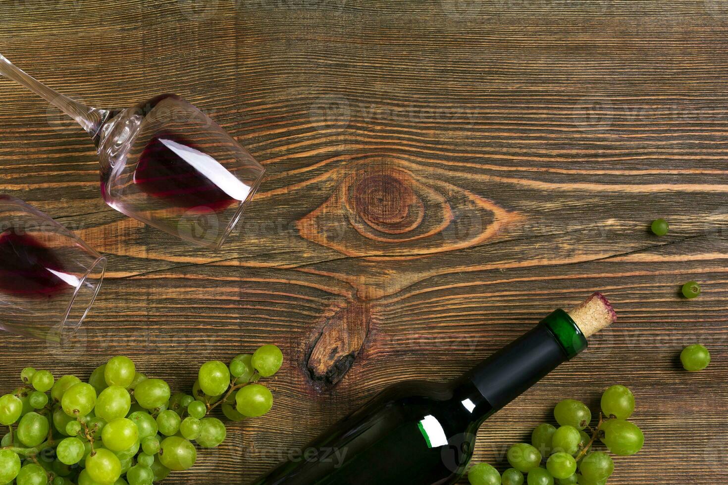 Red wine bottle, grape and glasses over wooden table. Top view with copy space photo