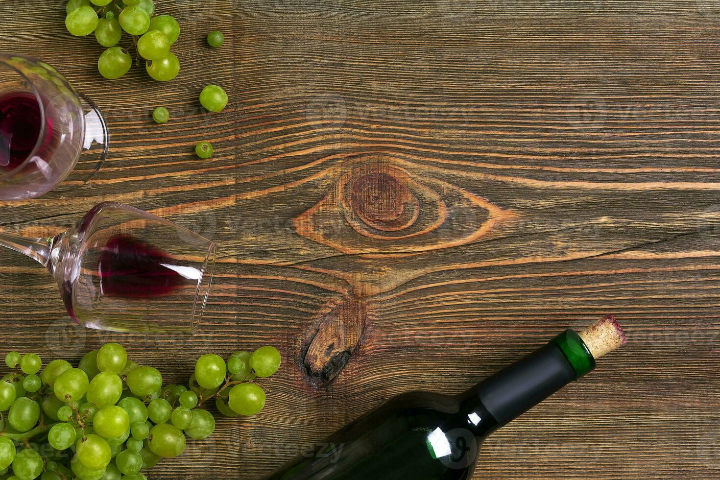 Two glasses, bottle of red wine and grape on a wooden table photo