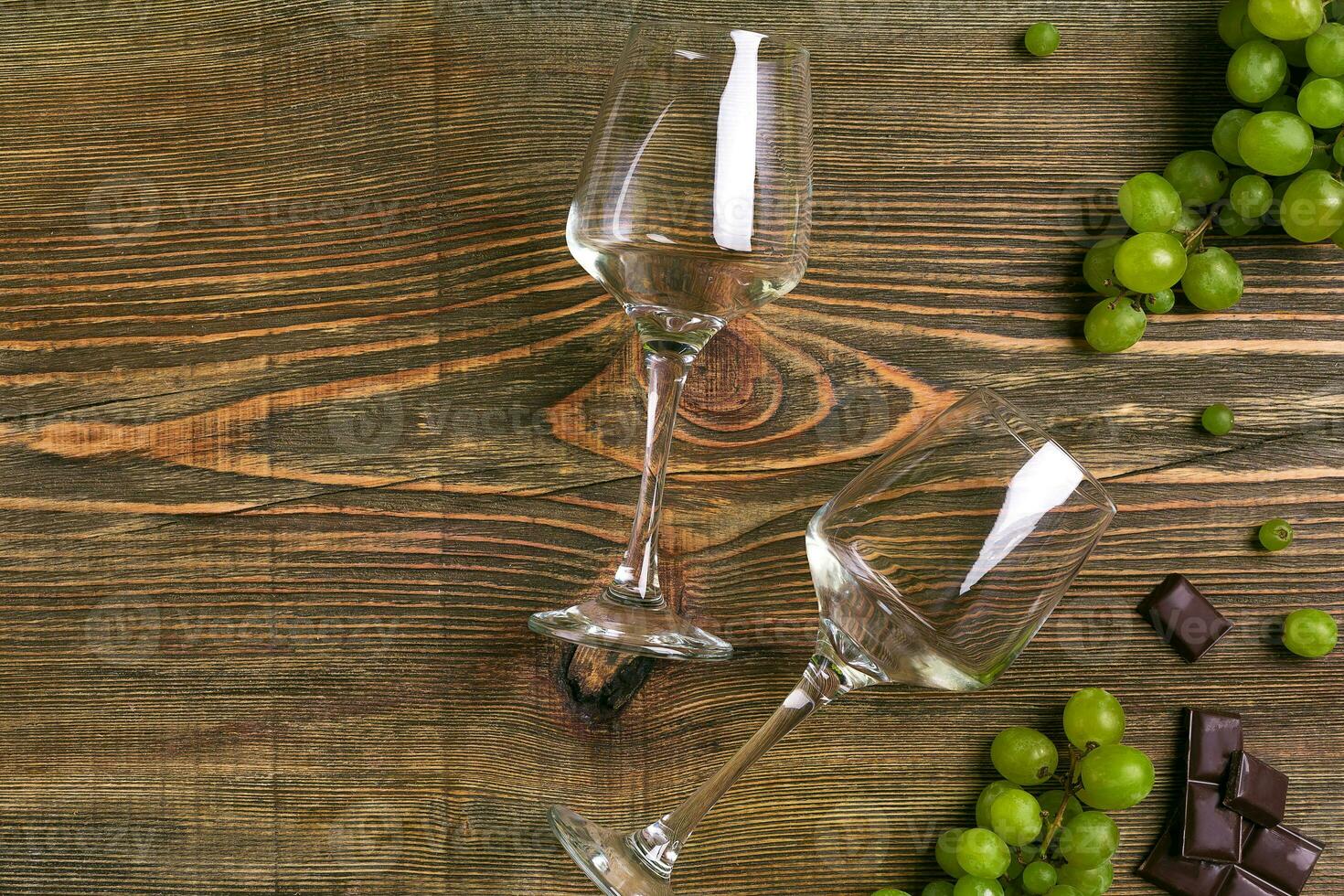 Glasses of wine and ripe grapes isolated on a wooden table photo