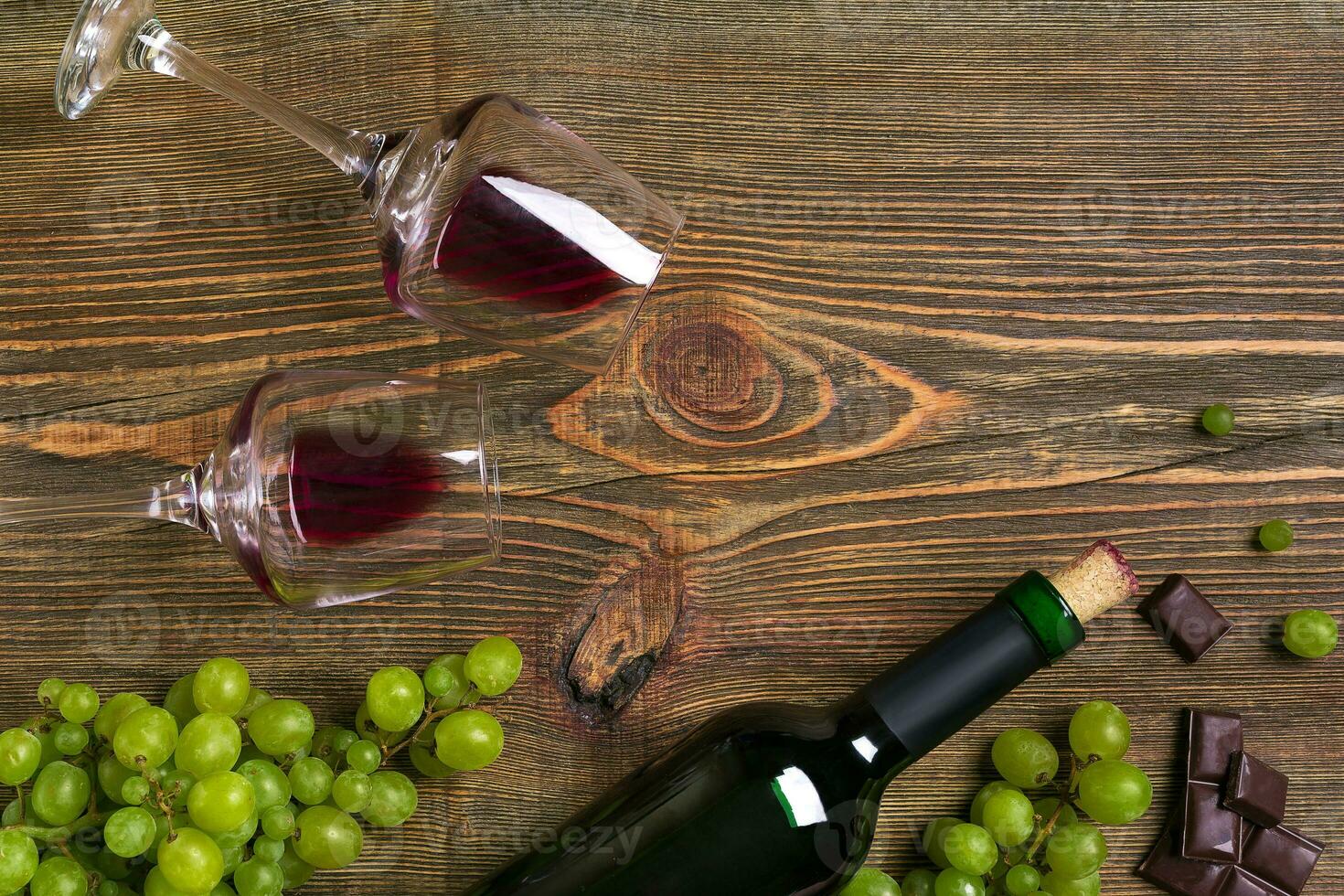 Two glasses, bottle of red wine and grape on a wooden table photo