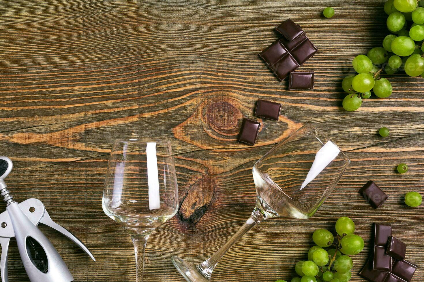 Glasses of wine and ripe grapes isolated on a wooden table photo