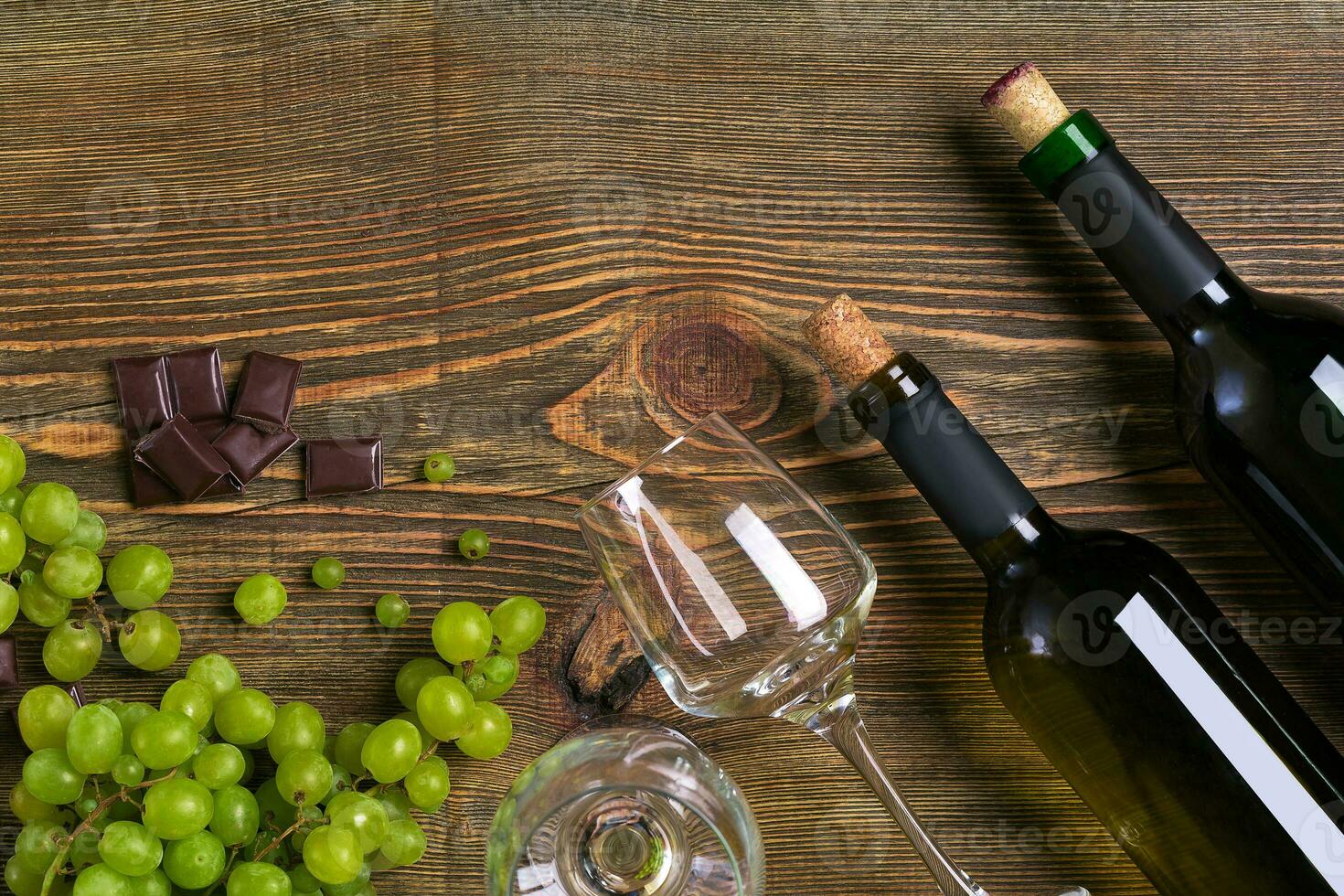 Bottles and glasses of wine, chocolate and ripe grapes on wooden background photo