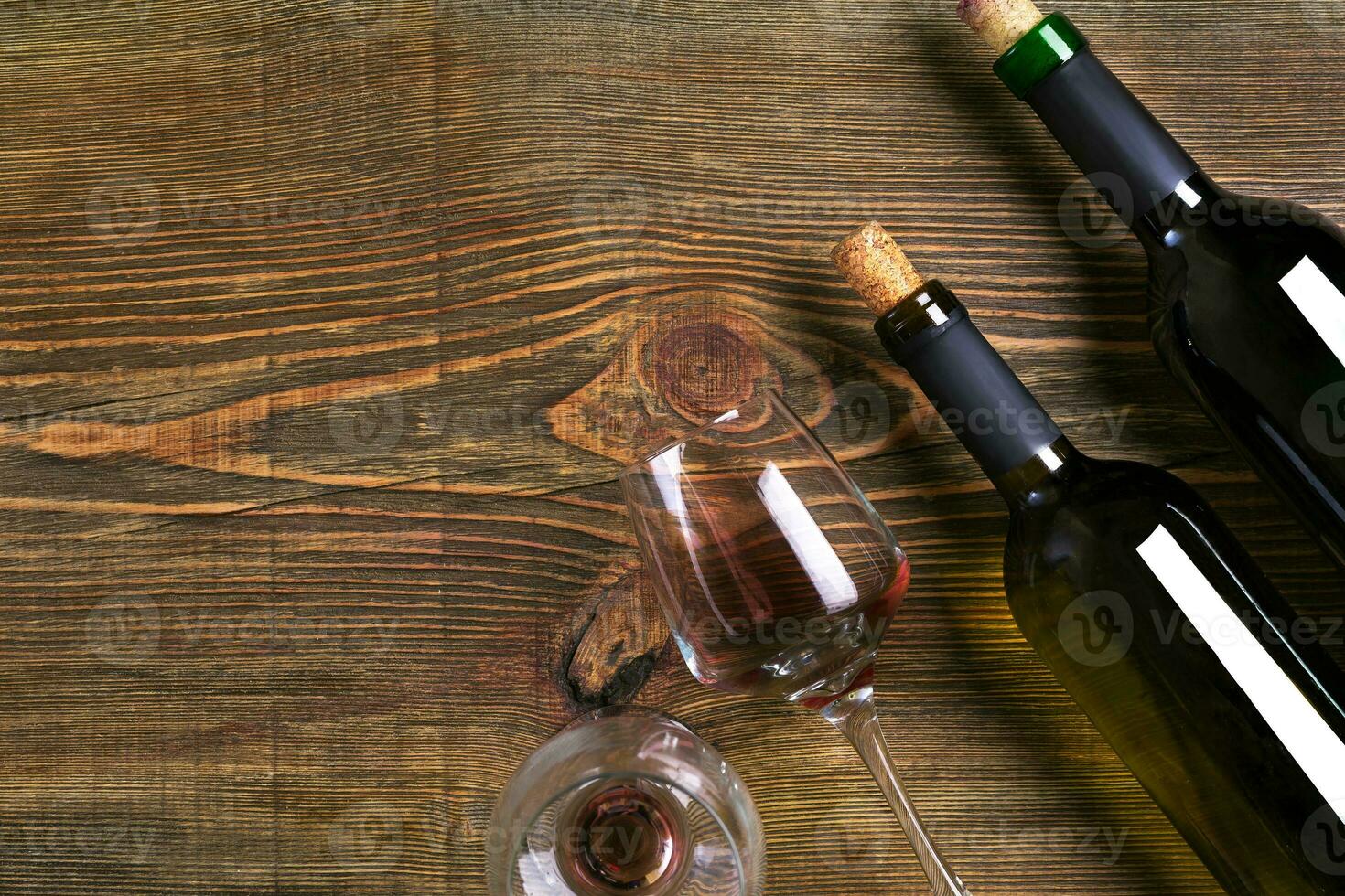 Bottles and two glasses of wine on wooden background from top view photo