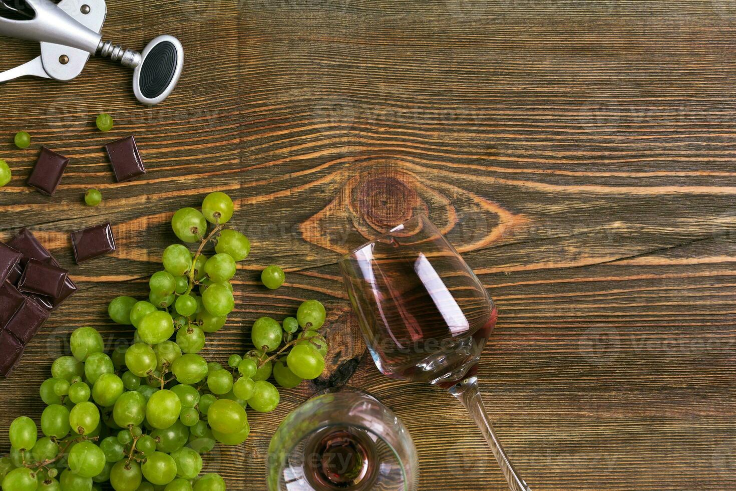 Two glasses of red wine, green grapes and chocolate, top view photo
