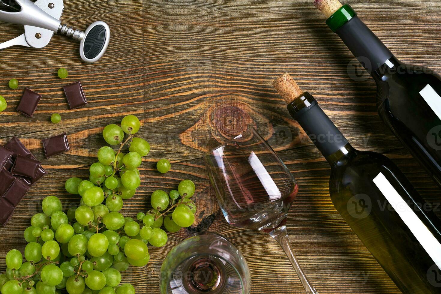 Bottles and glasses of wine, chocolate and ripe grapes on wooden background photo