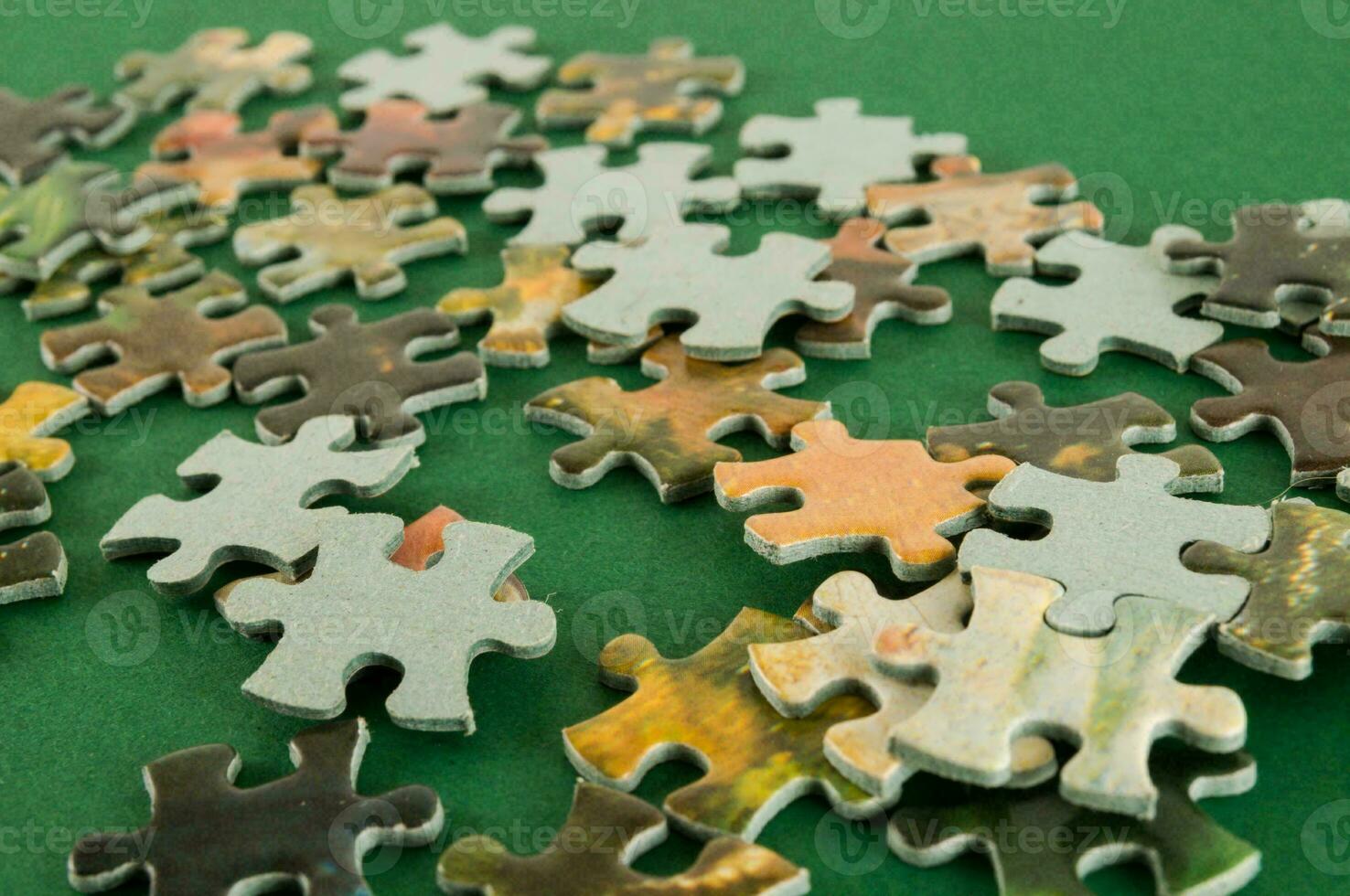 a pile of puzzle pieces on a green surface photo