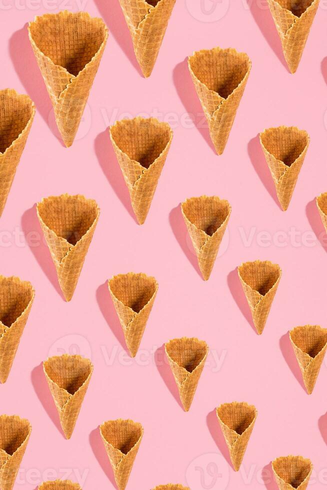 Sugar waffle cone for ice cream arranged in pattern on pink background. The image with copy space can be used as a background for the design of the confectionery menu photo