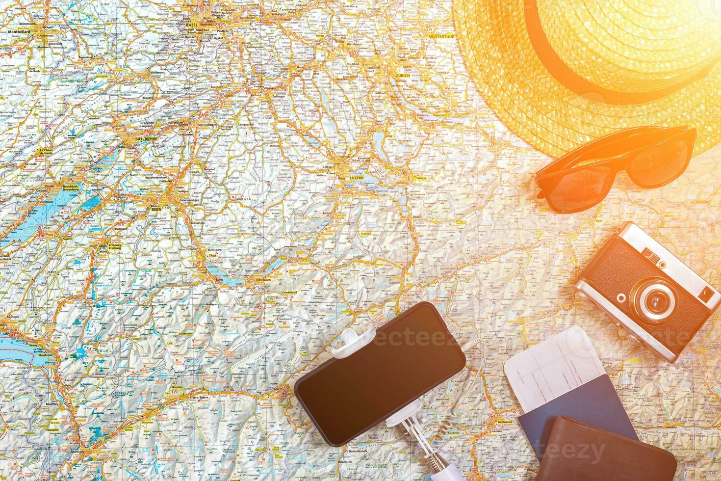 Accessories for travel. Passport, photo camera, smart phone and travel map. Top view. Sun flare