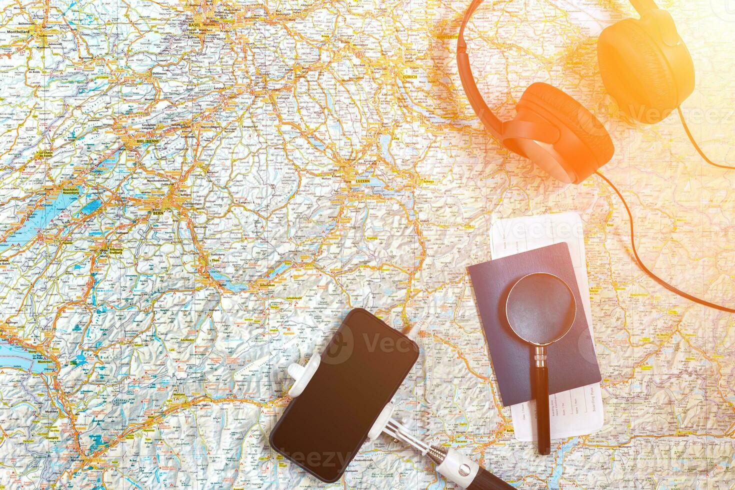 Accessories for travel. Passport, headphones, smart phone and travel map. Top view. Sun flare photo