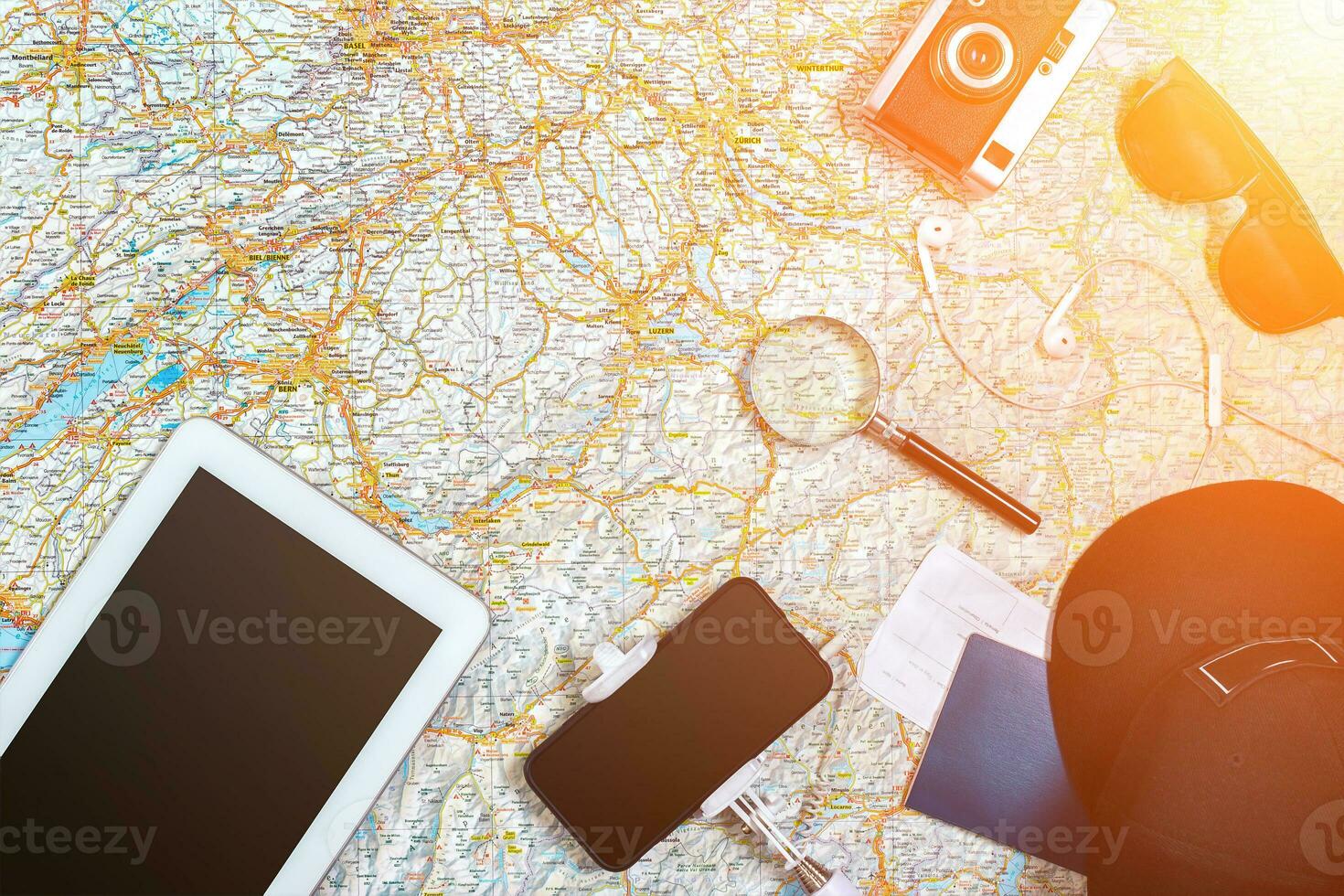 Accessories for travel. Passport, photo camera, smart phone and travel map. Top view. Sun flare