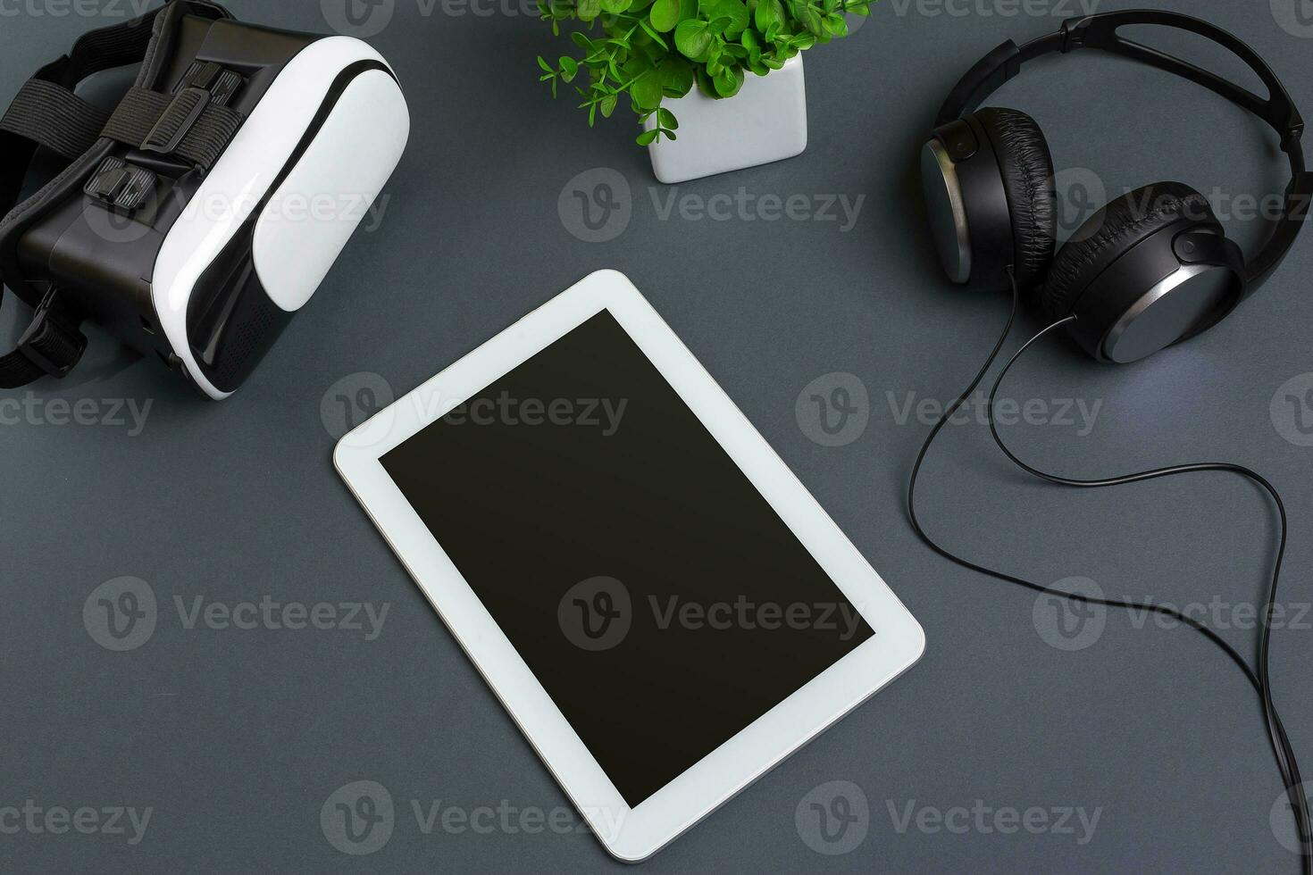 Virtual reality glasses and tablet with headphones on a gray background. Top view photo