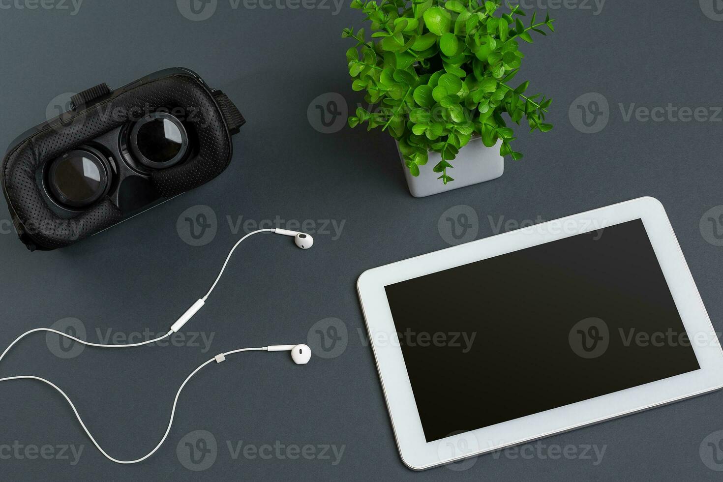 Virtual reality glasses and tablet with headphones on a gray background. Top view photo