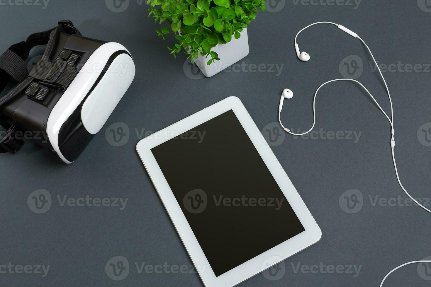 Virtual reality glasses and tablet with headphones on a gray background. Top view photo