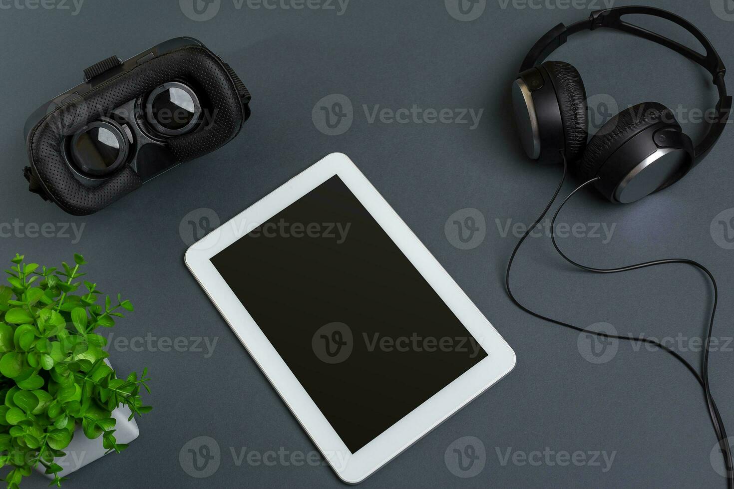 Virtual reality glasses and tablet with headphones on a gray background. Top view photo