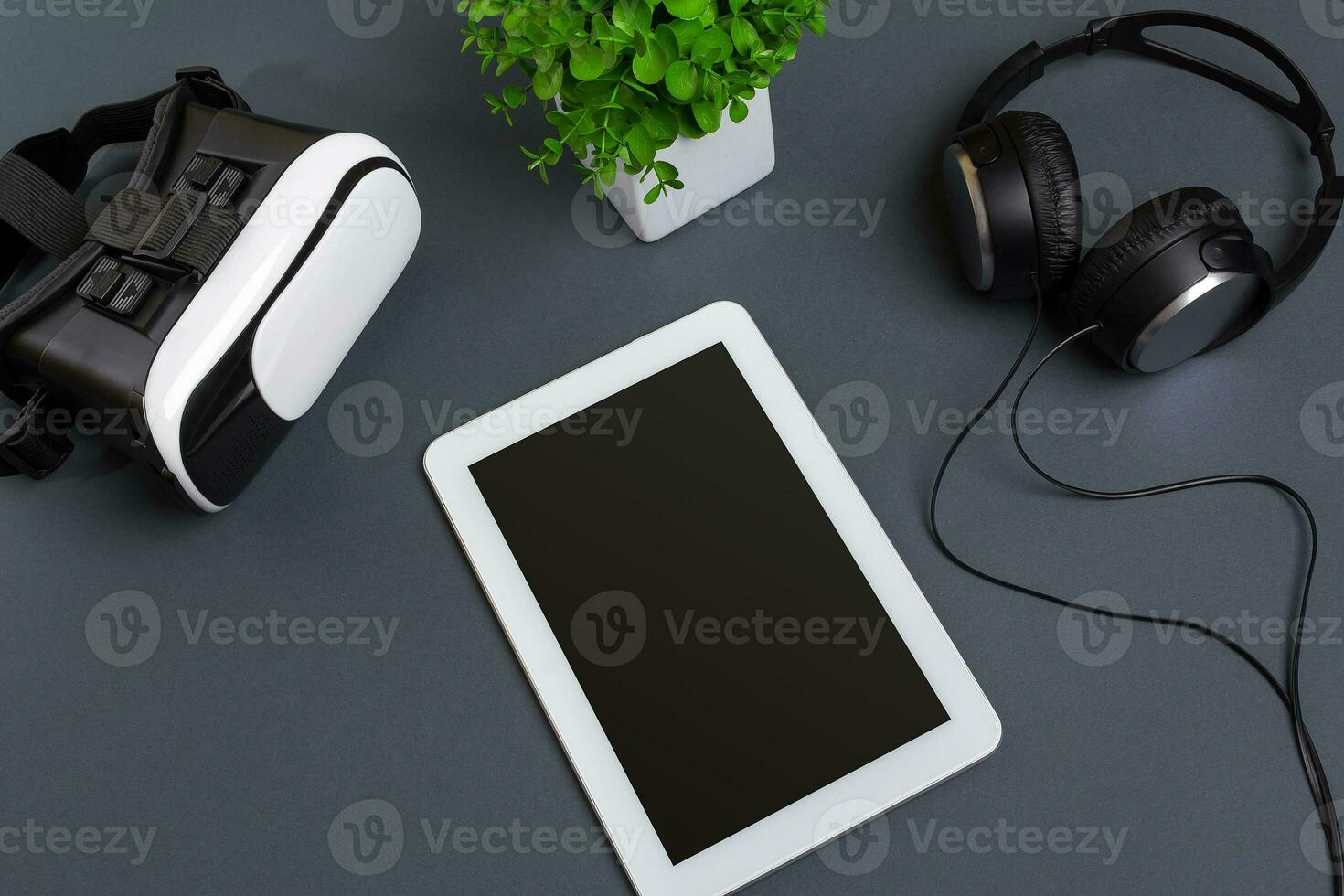 Virtual reality glasses and tablet with headphones on a gray background. Top view photo