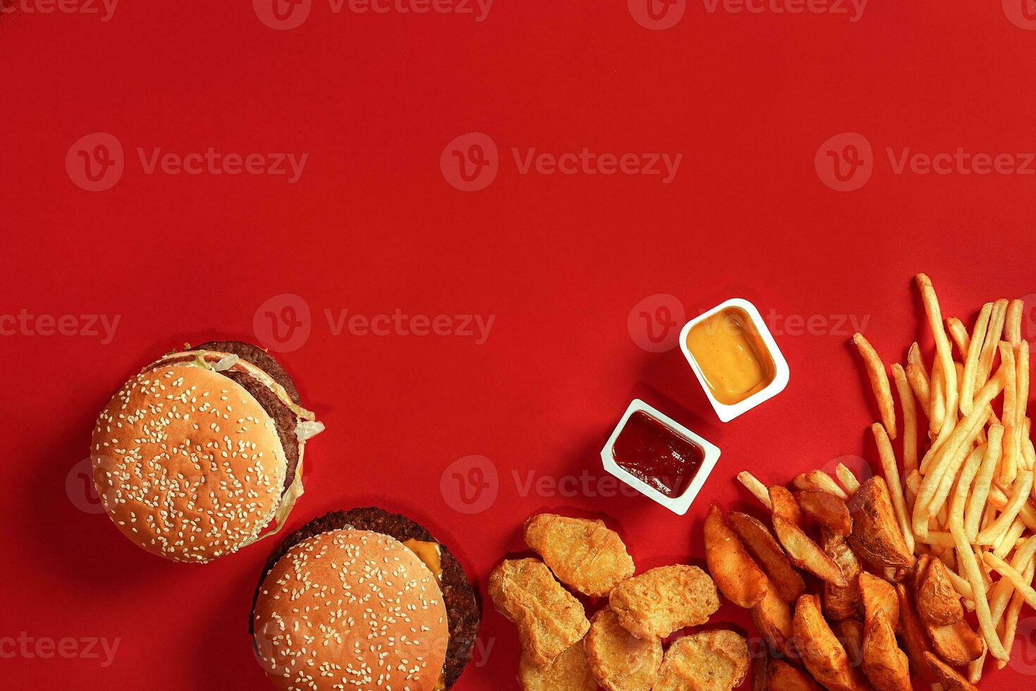 Fast food dish top view. Meat burger, potato chips and nuggets on red background. Takeaway composition. photo