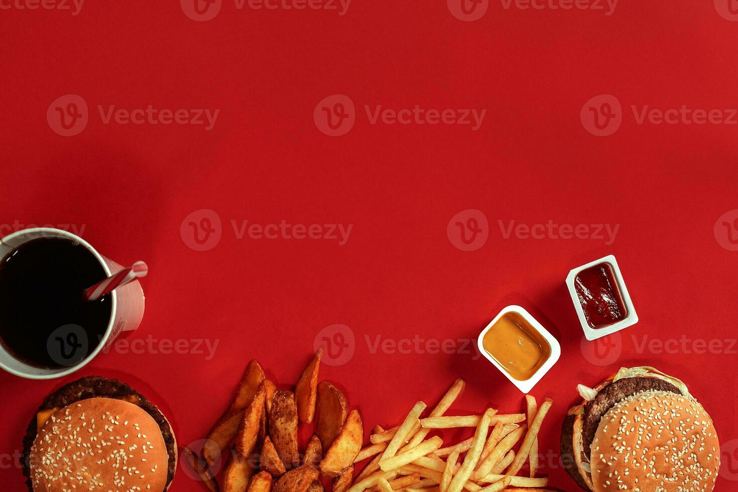 Fast food dish top view. Meat burger, potato chips and glass of drink on red background. Takeaway composition. photo