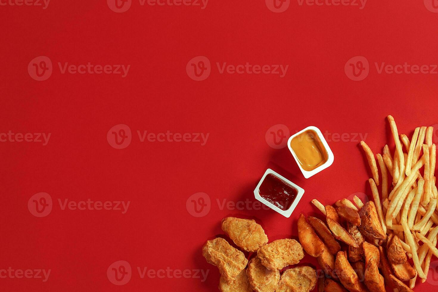 Nuggets and Chips. Nuggets and french fries in red paper box. Fast food on red background. photo