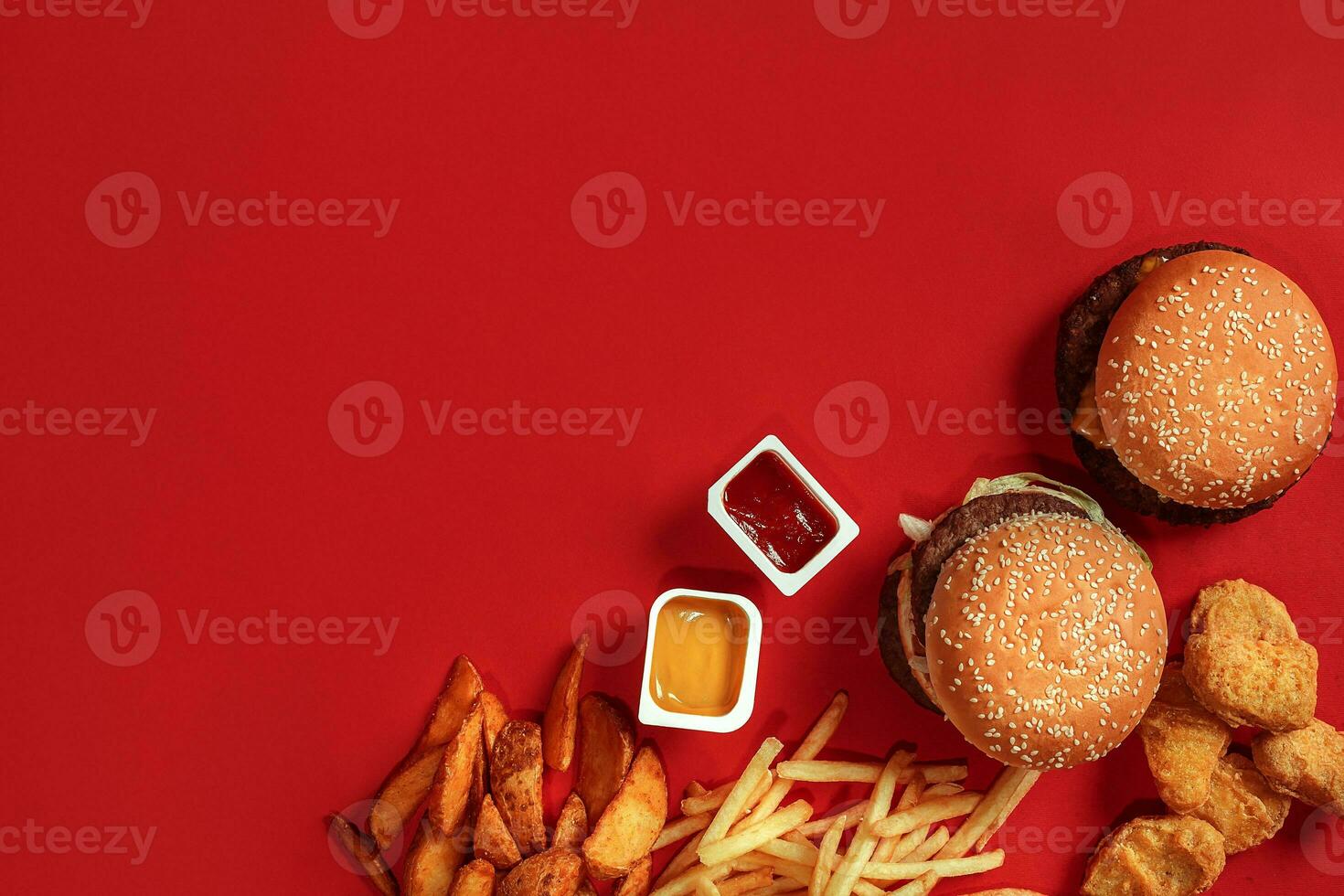 Fast food dish top view. Meat burger, potato chips and nuggets on red background. Takeaway composition. photo