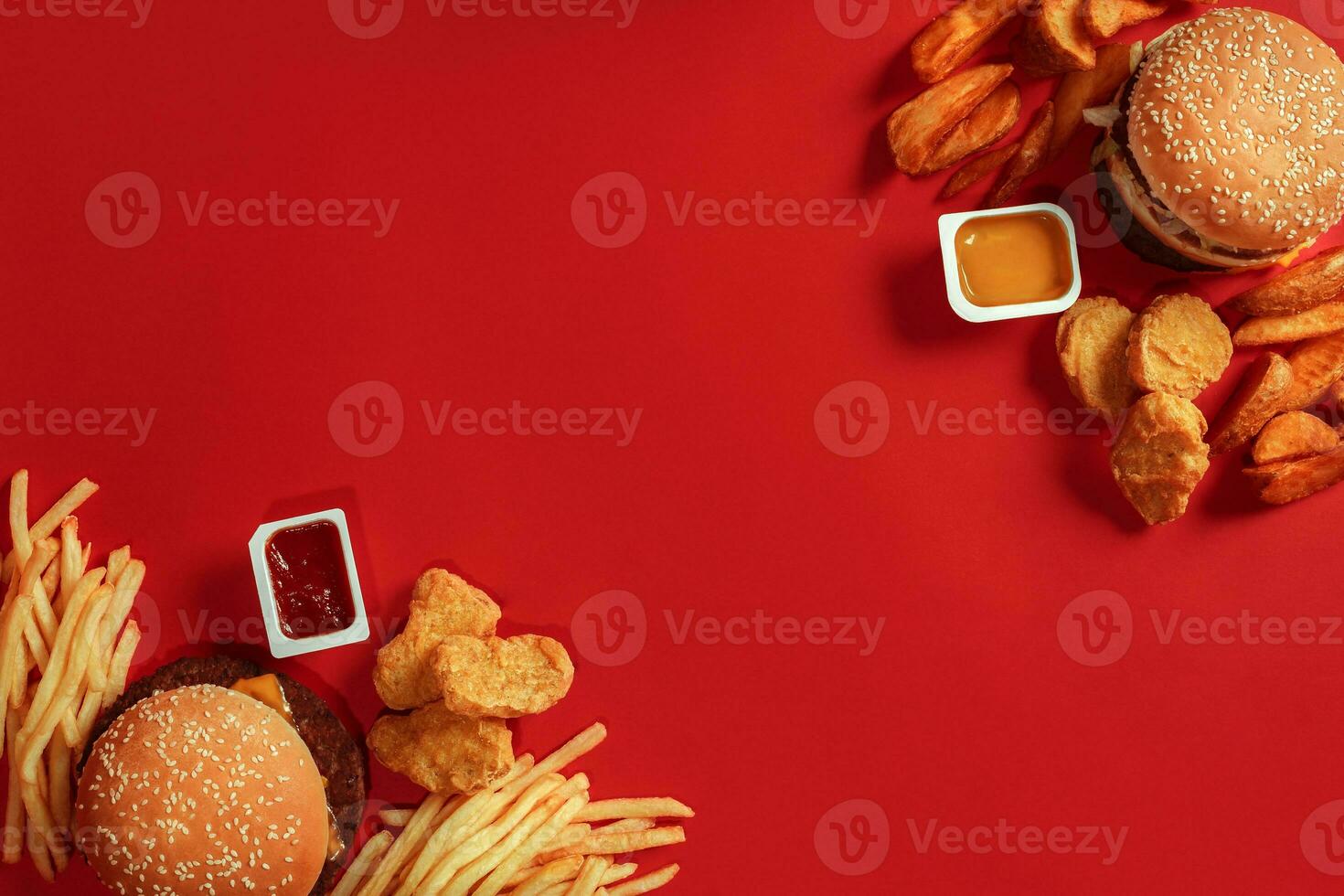 Two hamburgers and french fries, sauces on red background. Fast food. Top view. photo