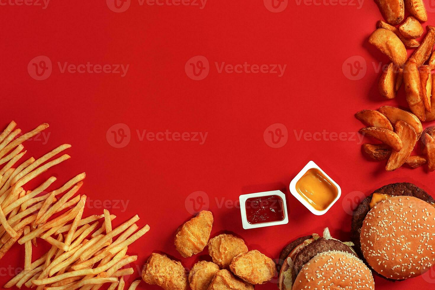 Fast food dish top view. Meat burger, potato chips and nuggets on red background. Takeaway composition. photo