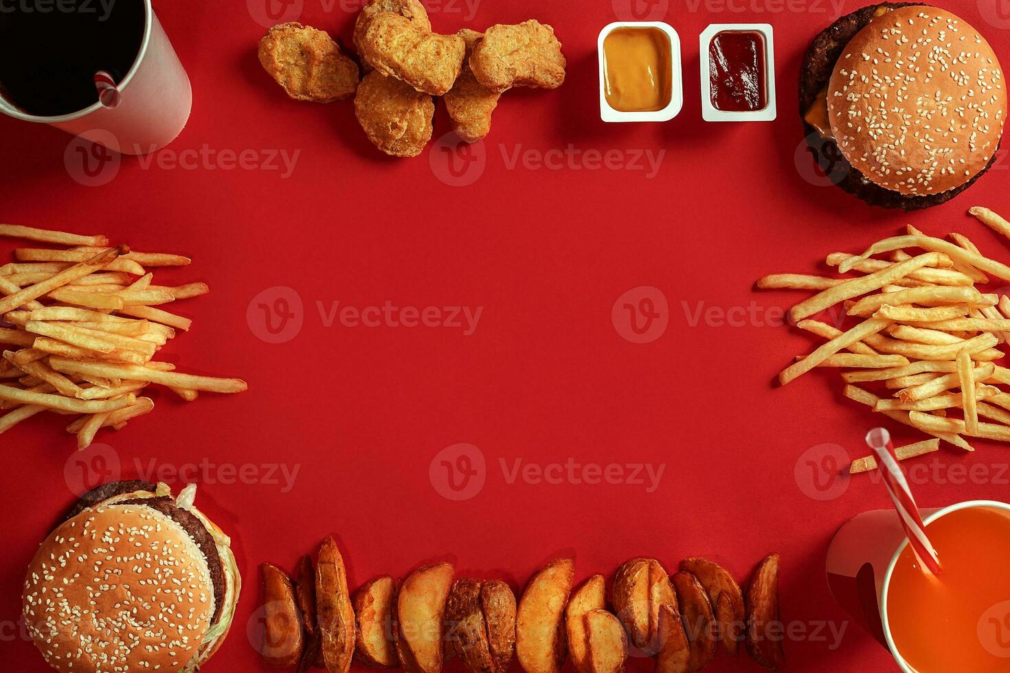 Two hamburgers and french fries, sauces and drinks on red background. Fast food. Top view, flat lay with copyspace photo