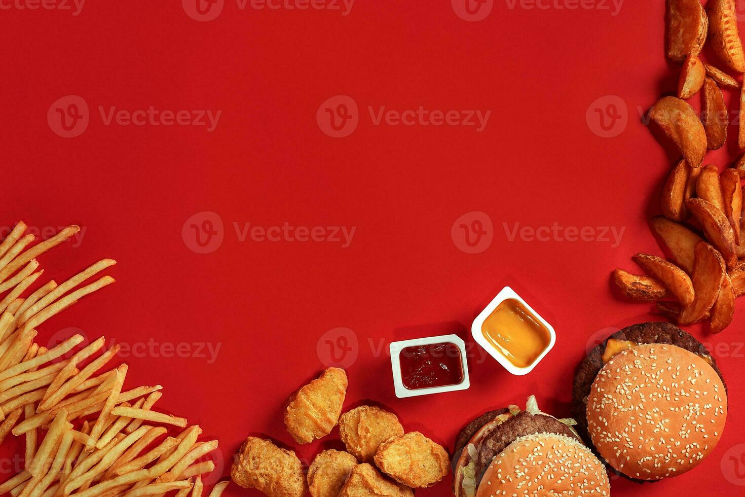 Fast food dish top view. Meat burger, potato chips and nuggets on red background. Takeaway composition. photo