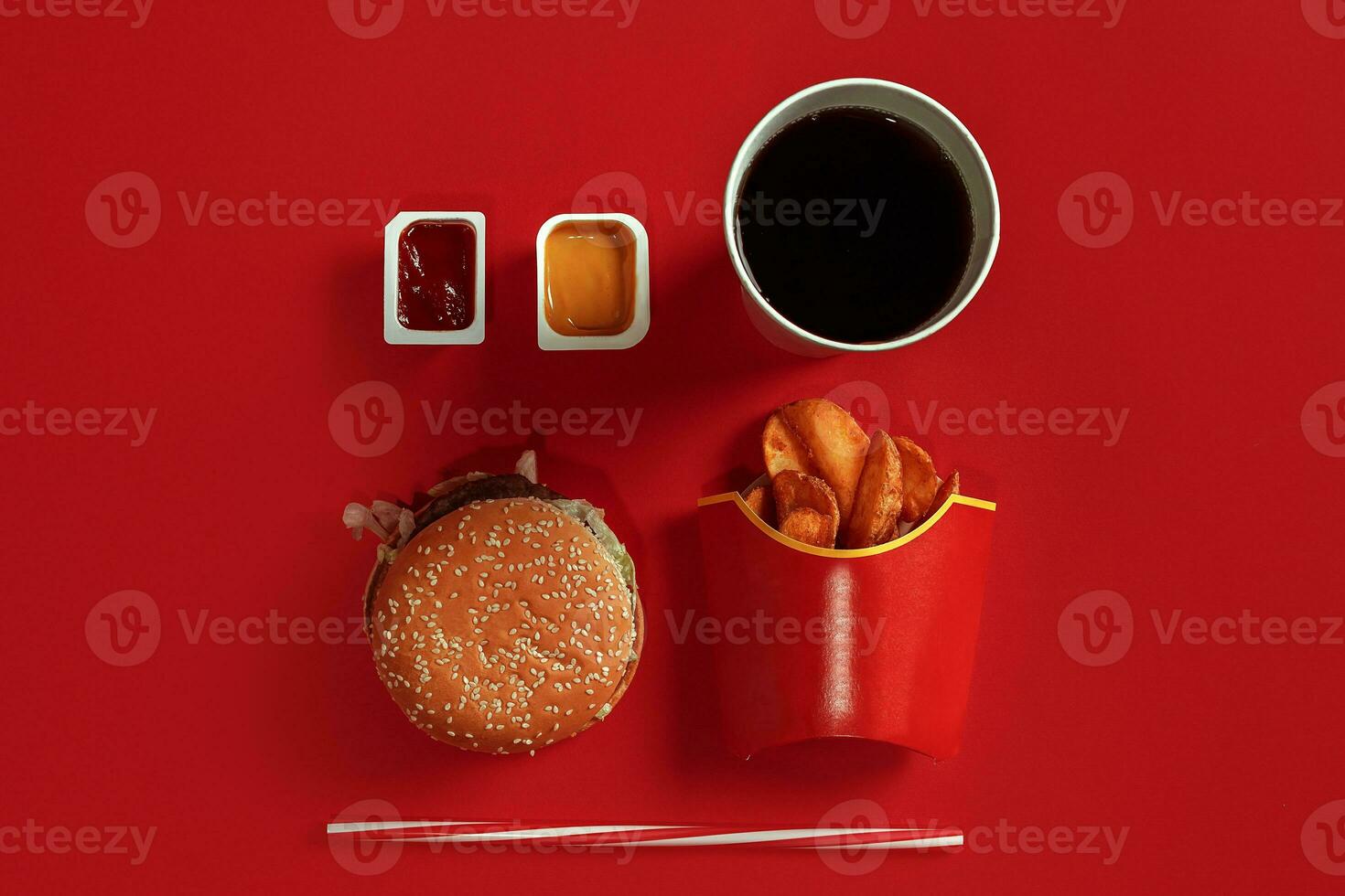 Fast food dish top view. Meat burger, potato chips and glass of drink on red background. Takeaway composition. photo