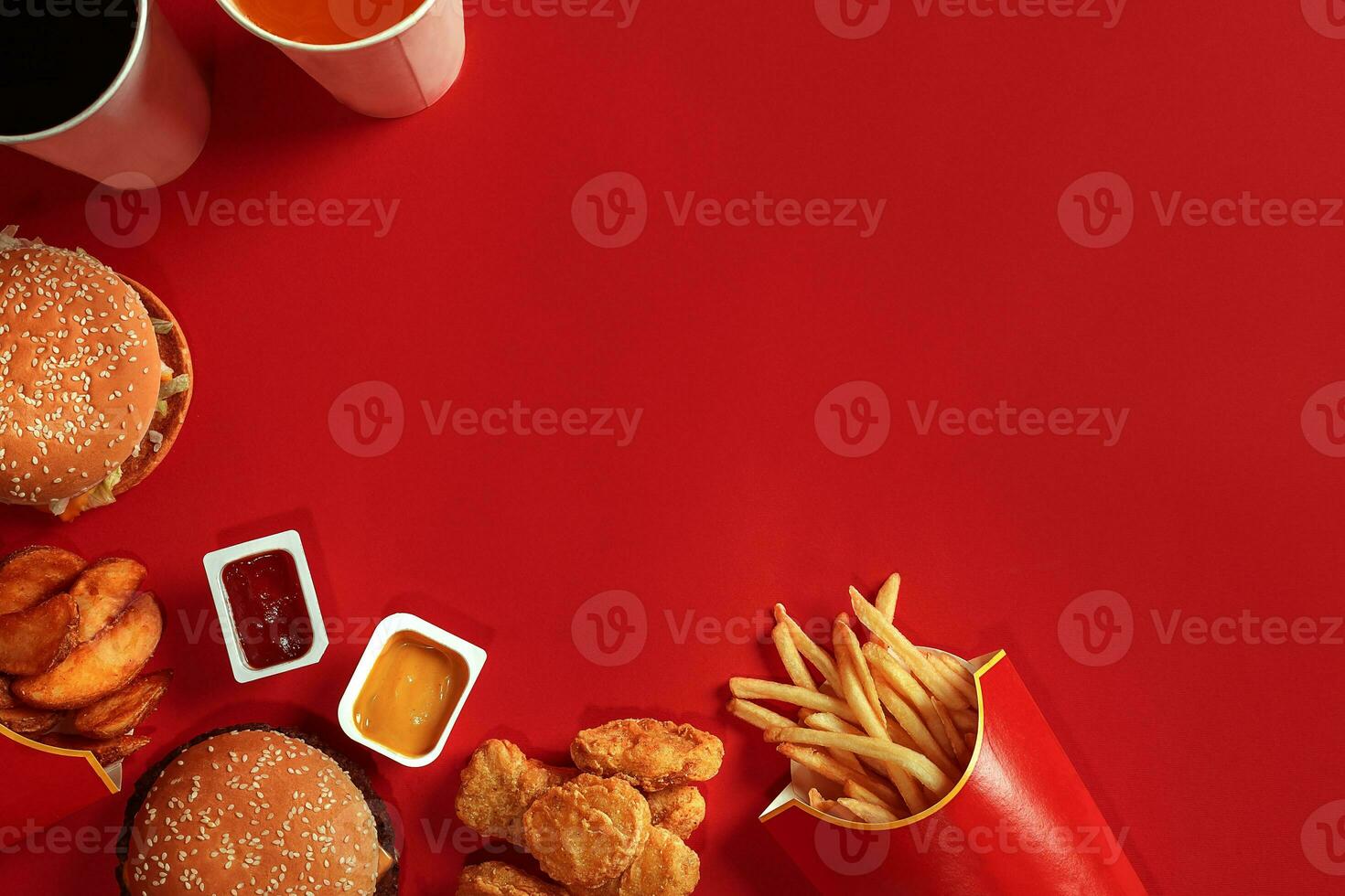 Fast food dish top view. Meat burger, potato chips and glass of drink on red background. Takeaway composition. photo