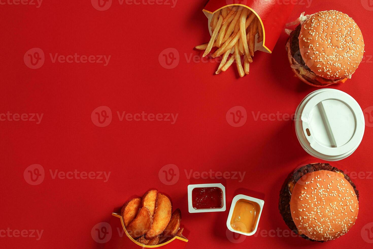 Fast food dish top view. Meat burger, potato chips and glass of drink on red background. Takeaway composition. photo