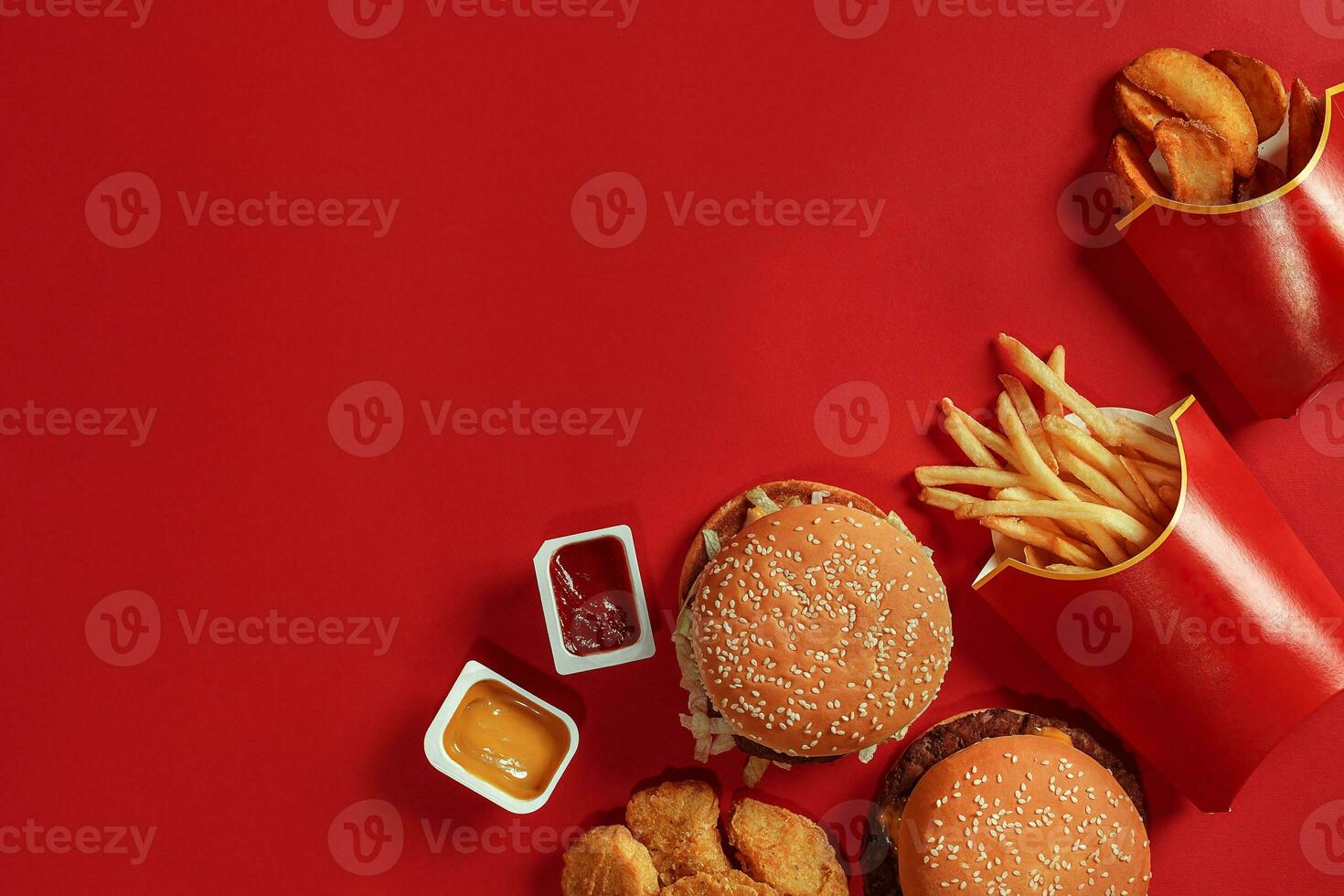 Two hamburgers and french fries, sauces on red background. Fast food. Top view. photo