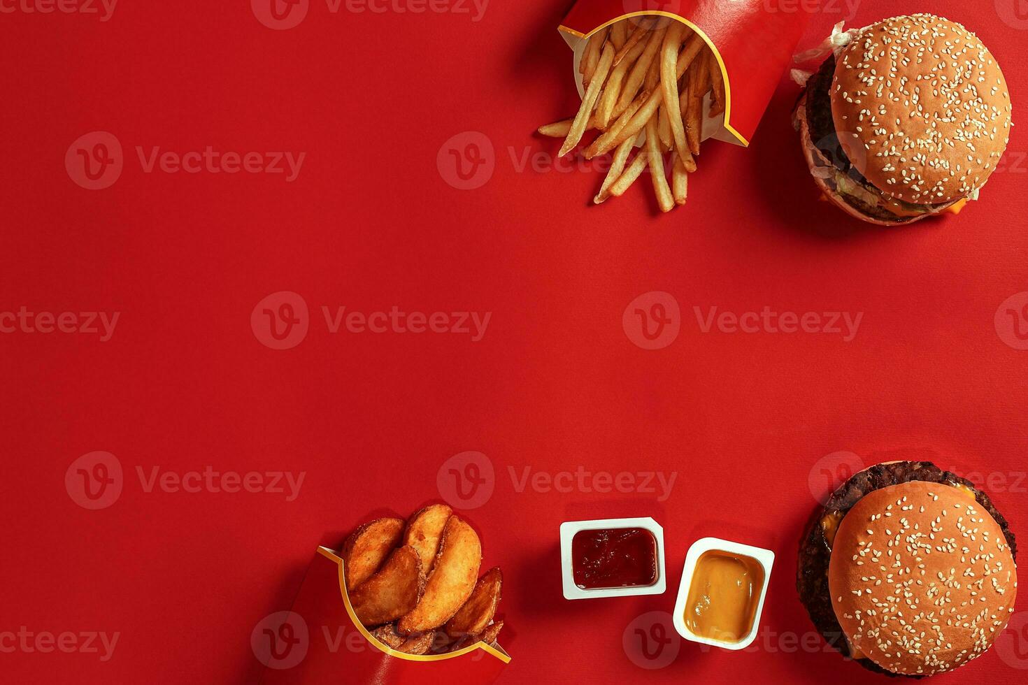 Two hamburgers and french fries, sauces on red background. Fast food. Top view. photo