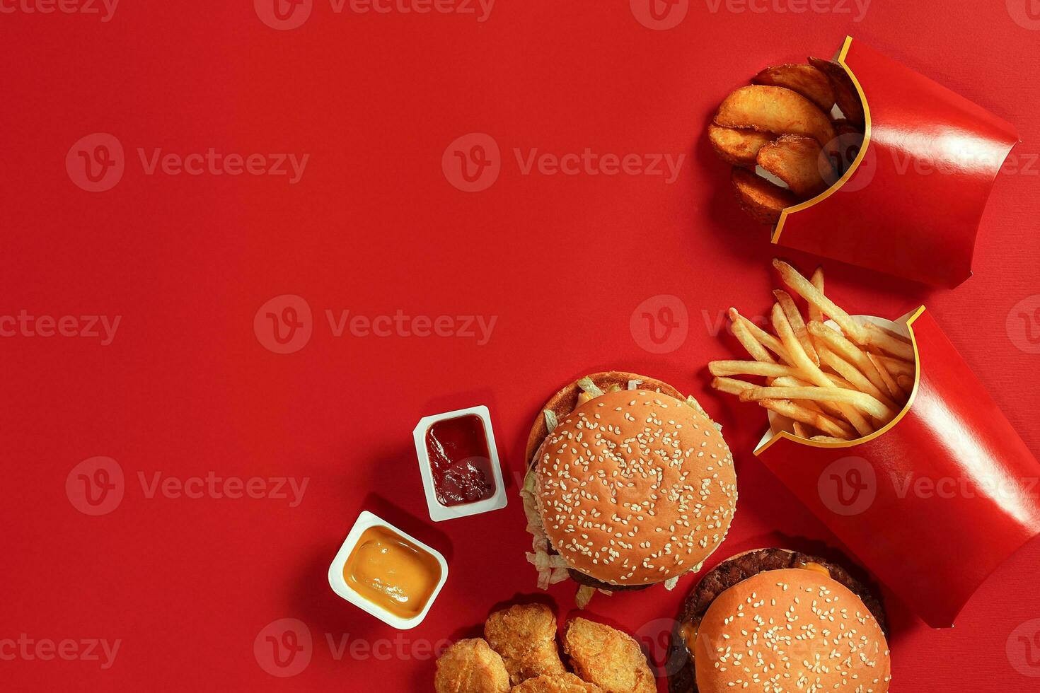 Fast food dish top view. Meat burger, potato chips and nuggets on red background. Takeaway composition. photo
