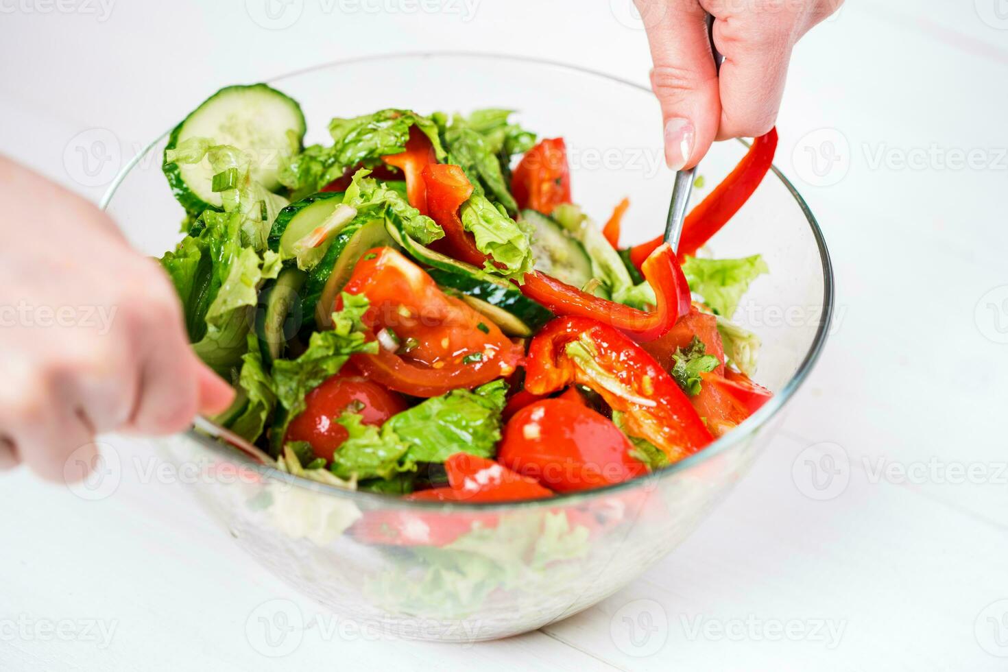 Young woman dressing vegetable salad with olive oil on a white background photo