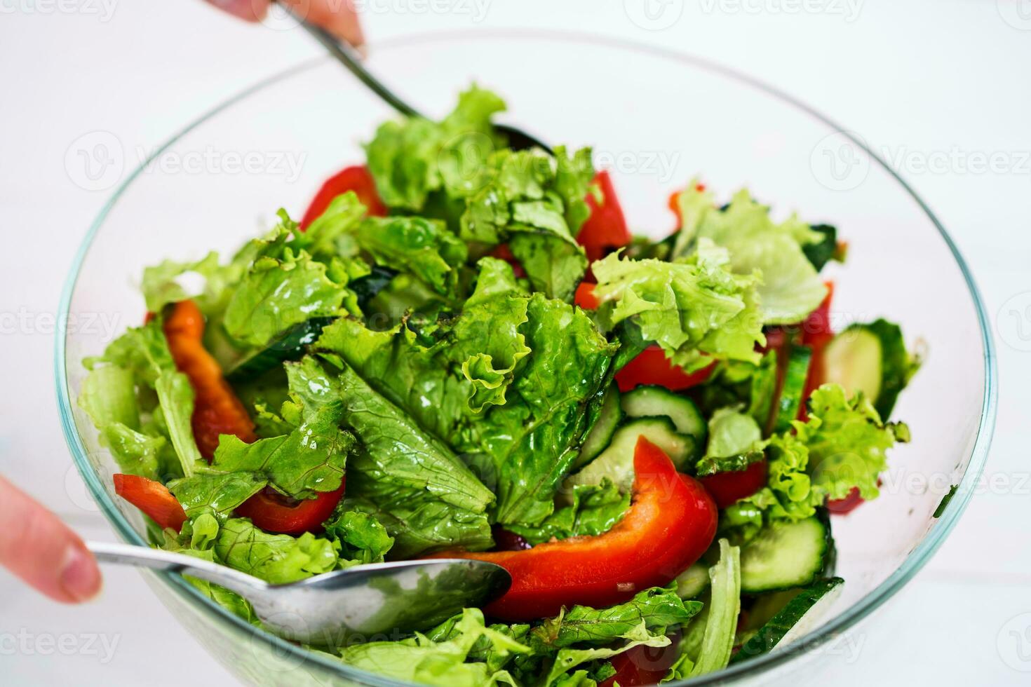 Young woman dressing vegetable salad with olive oil on a white background photo