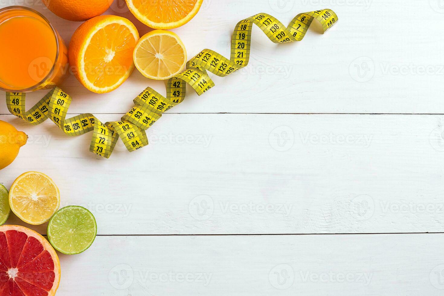 Fresh fruits with tape measure over white wooden background. Top view photo
