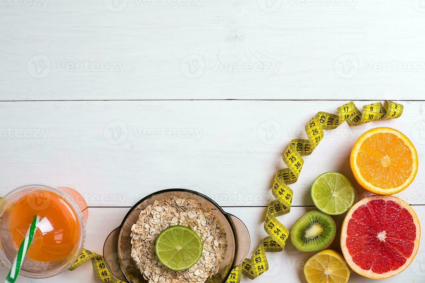 Fresh fruits with tape measure over white wooden background. Top view photo